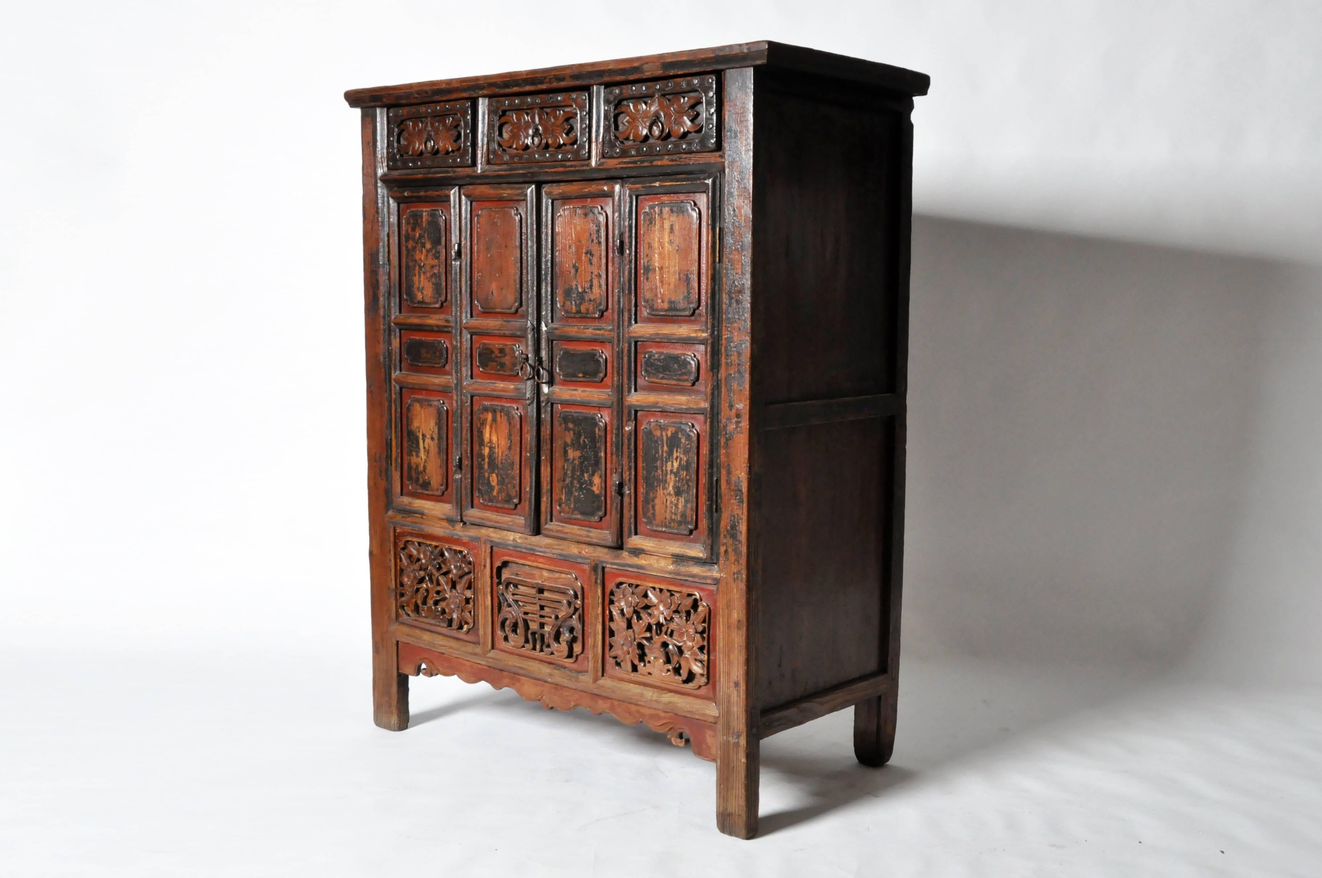 This Chinese oxblood lacquer cabinet is from China and is made from elmwood and oxblood lacquer, mid-19th century. It features bi-fold doors, three drawers for storage, and a hidden compartment underneath inside the cabinet.