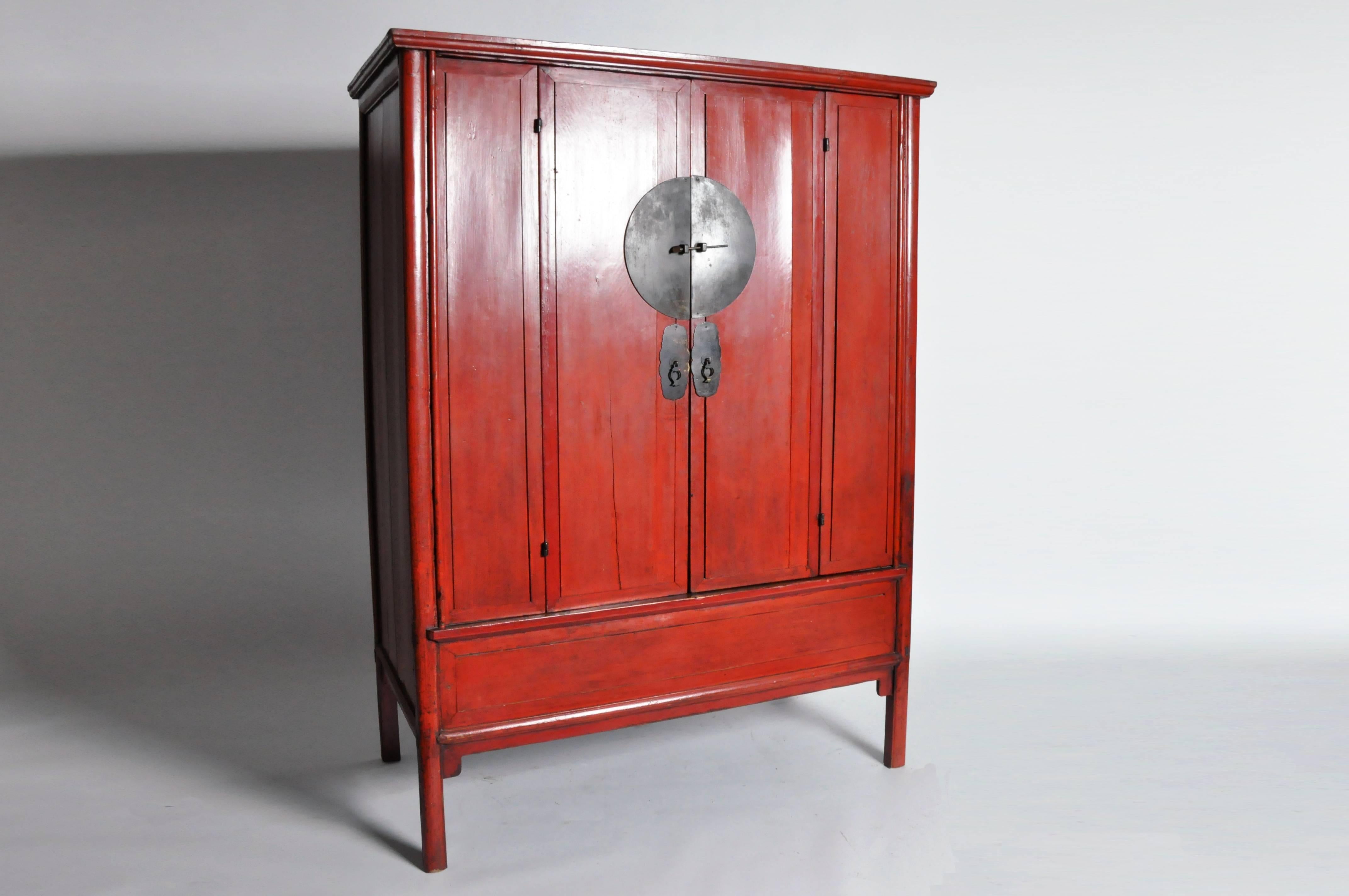 This impressive Chinese armoire is made from red lacquer over elmwood. This piece features with two bi-fold doors, two shelves, and a hidden compartment below.