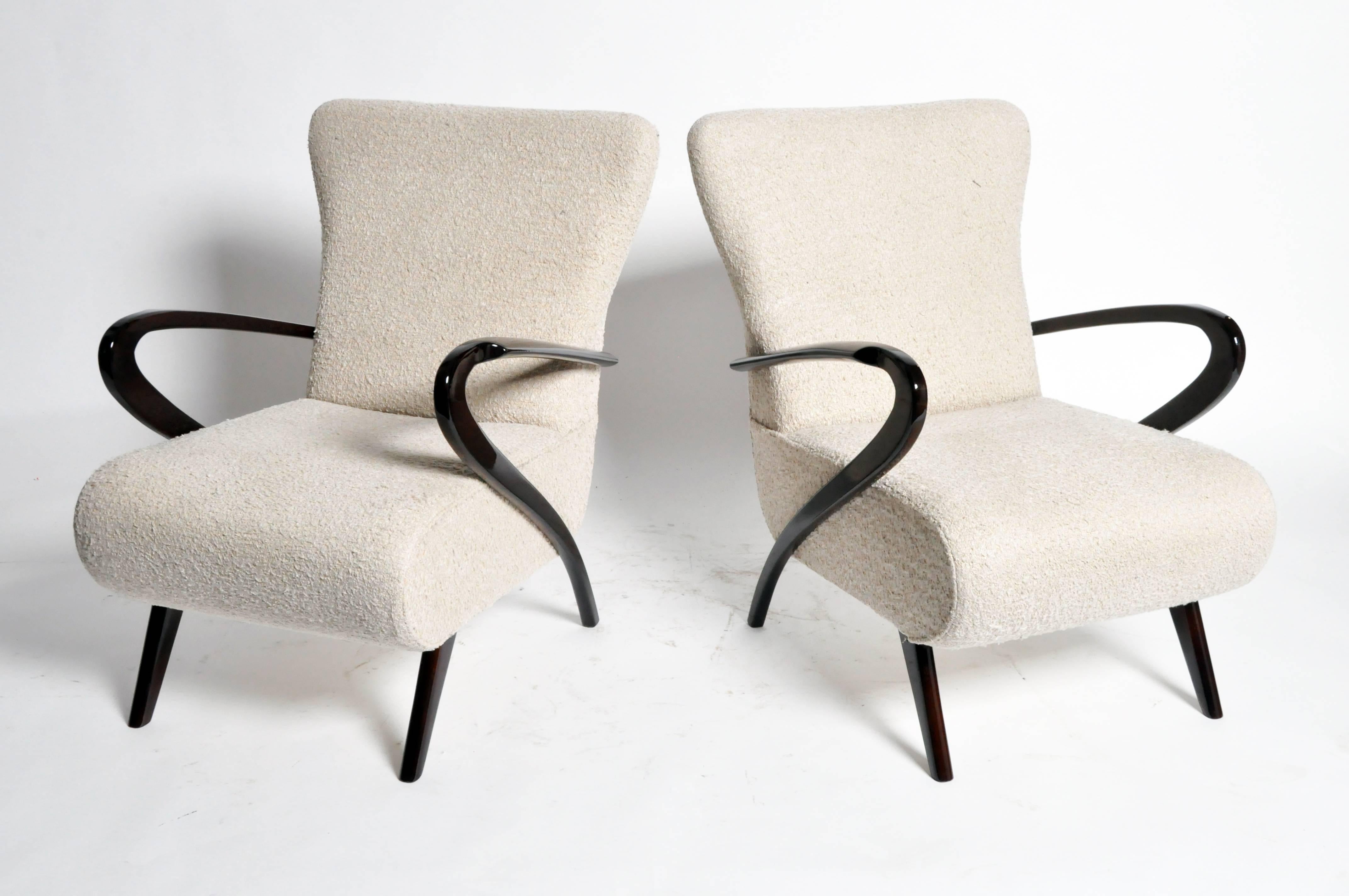 This stylish pair of Italian chairs features a winning combination of sleek, sculptural elements and bold, modernist design. Arms are finished in a pristinely polished, black walnut veneer. Ample seating in lambskin upholstery contributes to a fun,