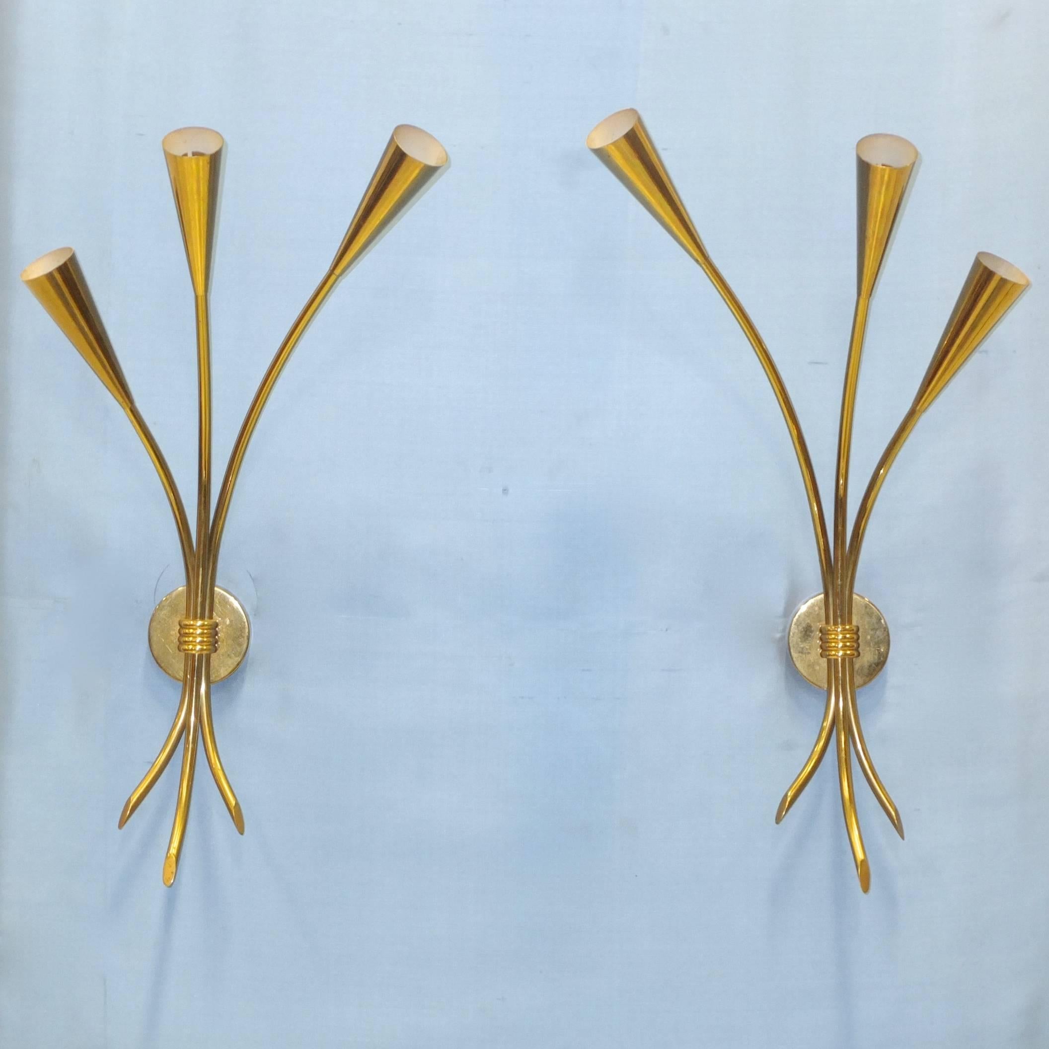 Pair of 1950s solid brass three-arm sconces by Lunel, model 701/3. In the form of a three stem bouquet of tulips with solid brass cones which taper evenly to the stem. Round brass backplate with signature Lunel four band brass ring clutching the
