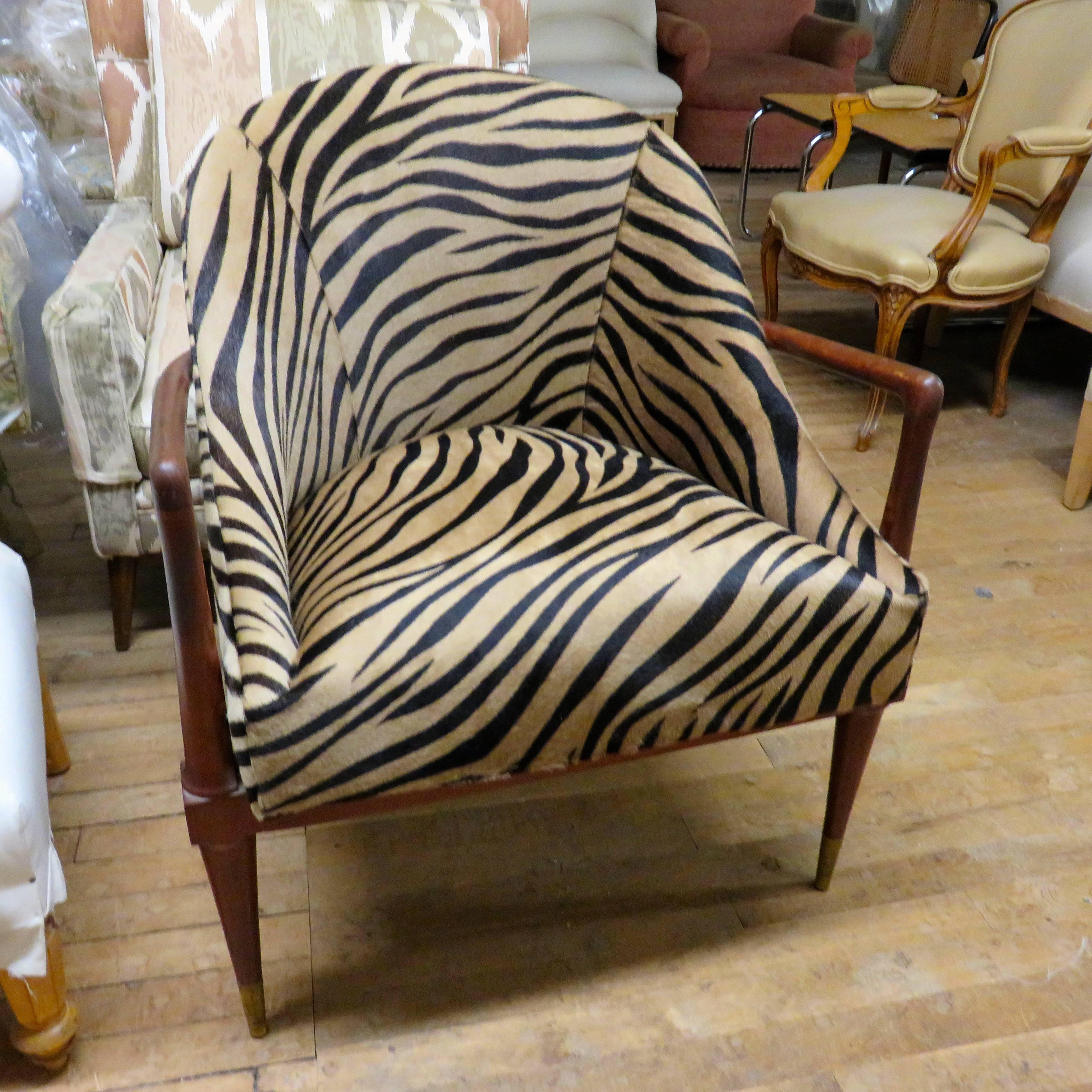 Stunningly handsome single arm chair in the style of T. H. Robsjohn Gibbings with sculptural solid walnut frames, curved seat back, sloping sides and high brass sabots. 

Newly reupholstered in zebra printed cowhide.