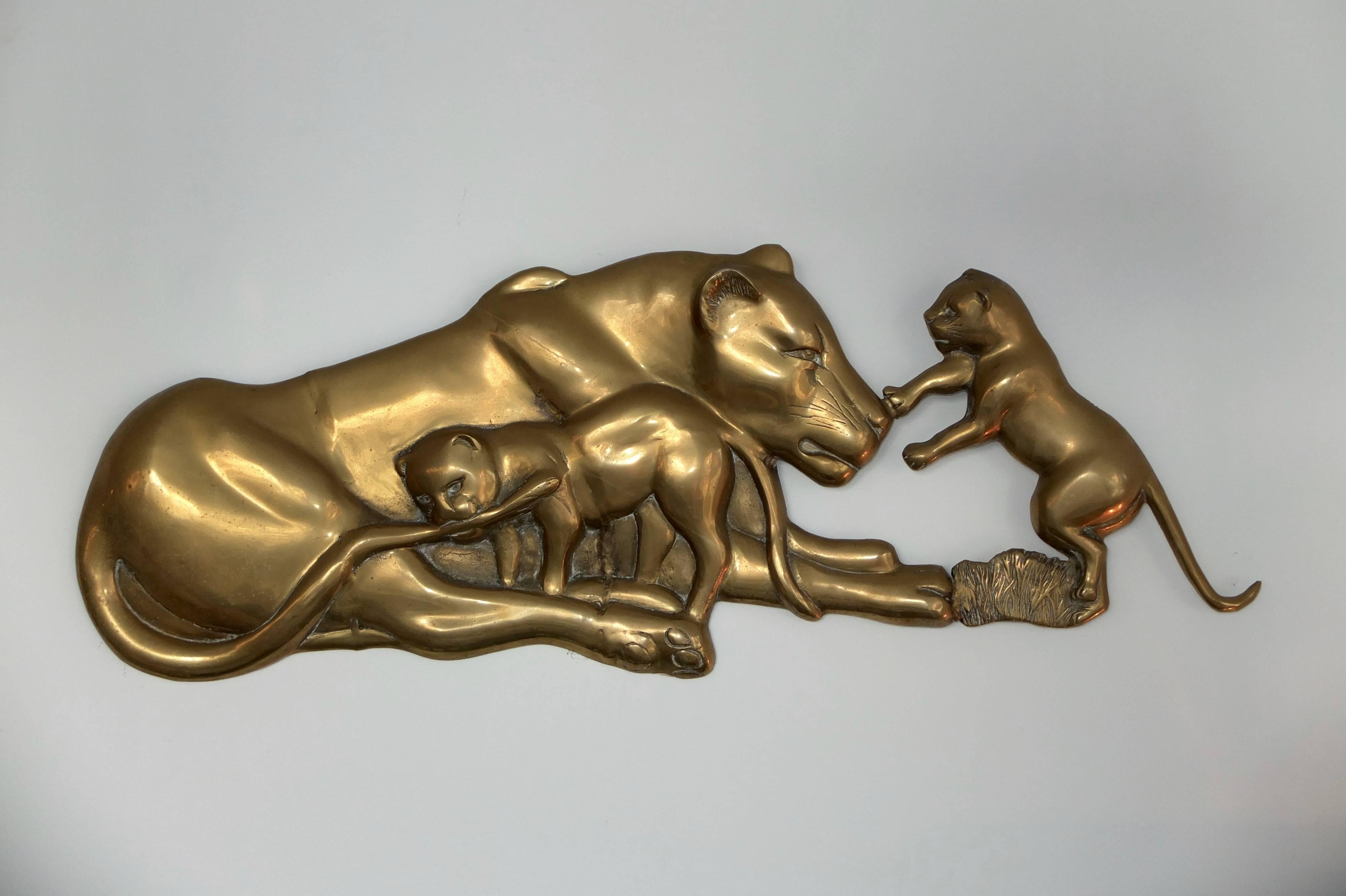 Sculptural solid brass cast relief of a lioness with her two young playful cubs.  Fitted with a chain on the back for hanging on a wall.  Original vintage patina.
