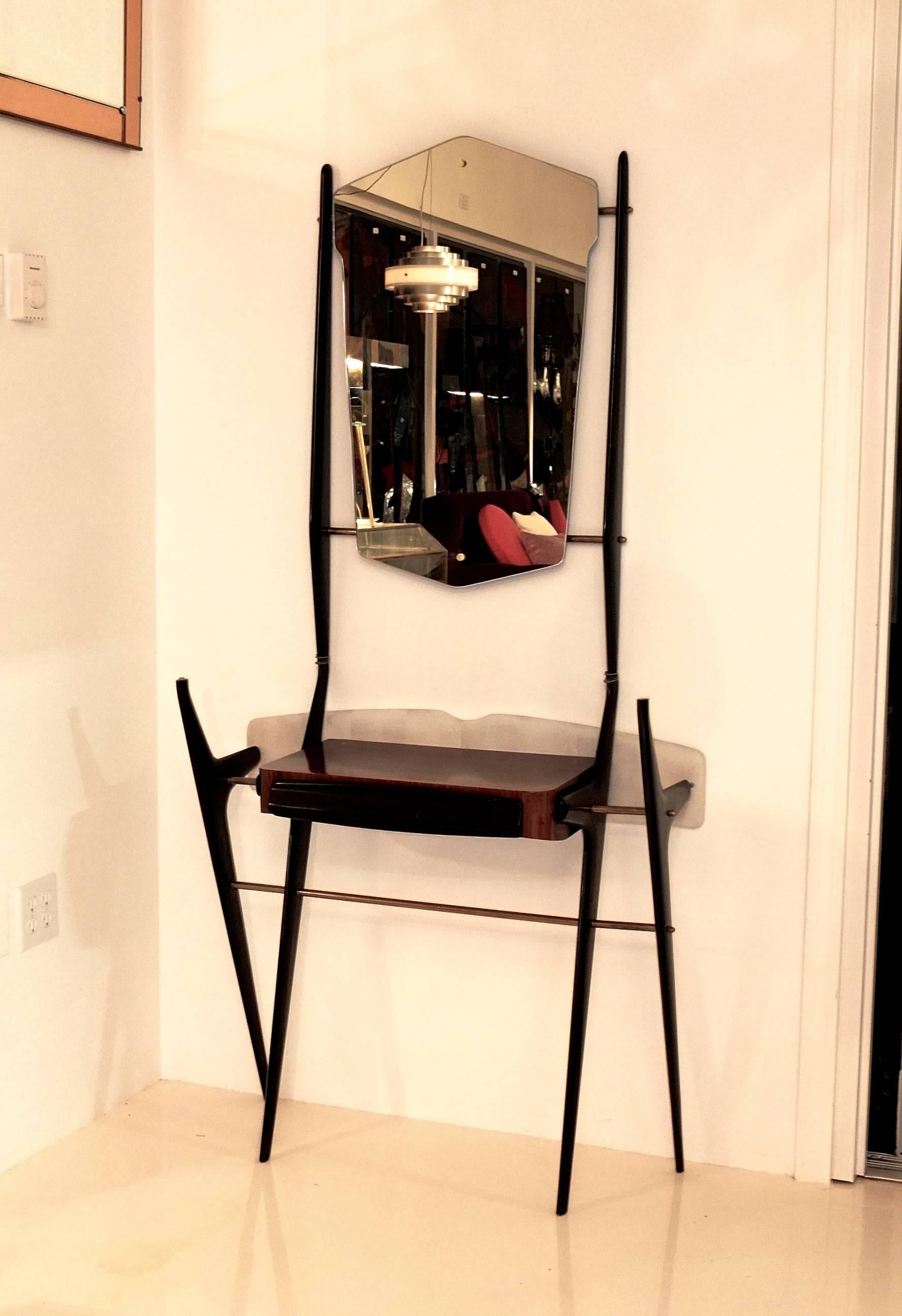 Striking scissor-legged hallway console with lacquered fruitwood single drawer case and mounted glass shelf supported by brass clips. Textured Skai covered back board mounts to wall to secure the piece in place. Research shows this is primarily