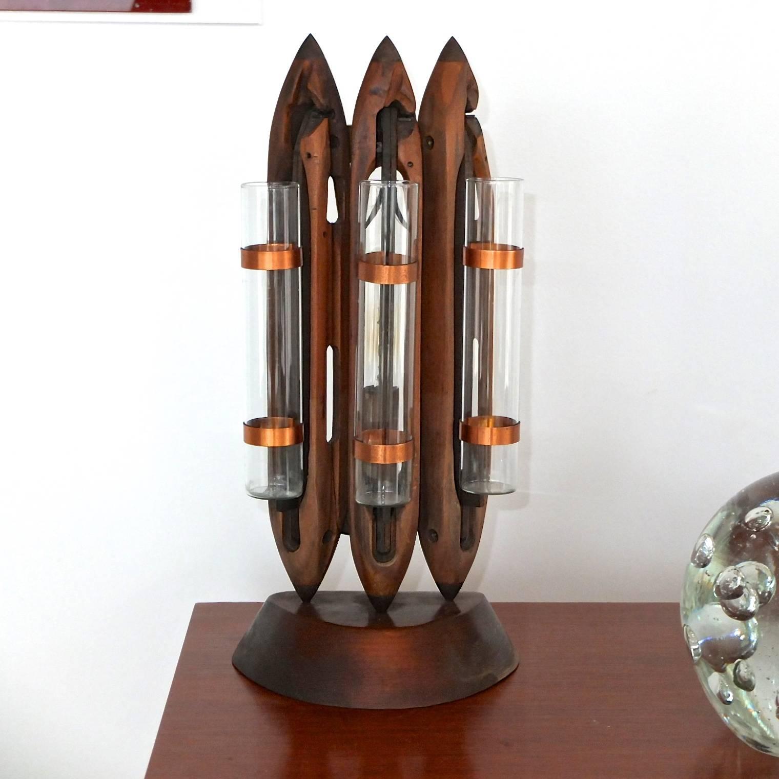 Vintage folk art table lamp made in the mid-20th century from three brass tipped weaving shuttles on a matching wood stand. Affixed to each shuttle by two copper ring clips is a glass tube for use as a bud vase. Behind the middle shuttle is a single