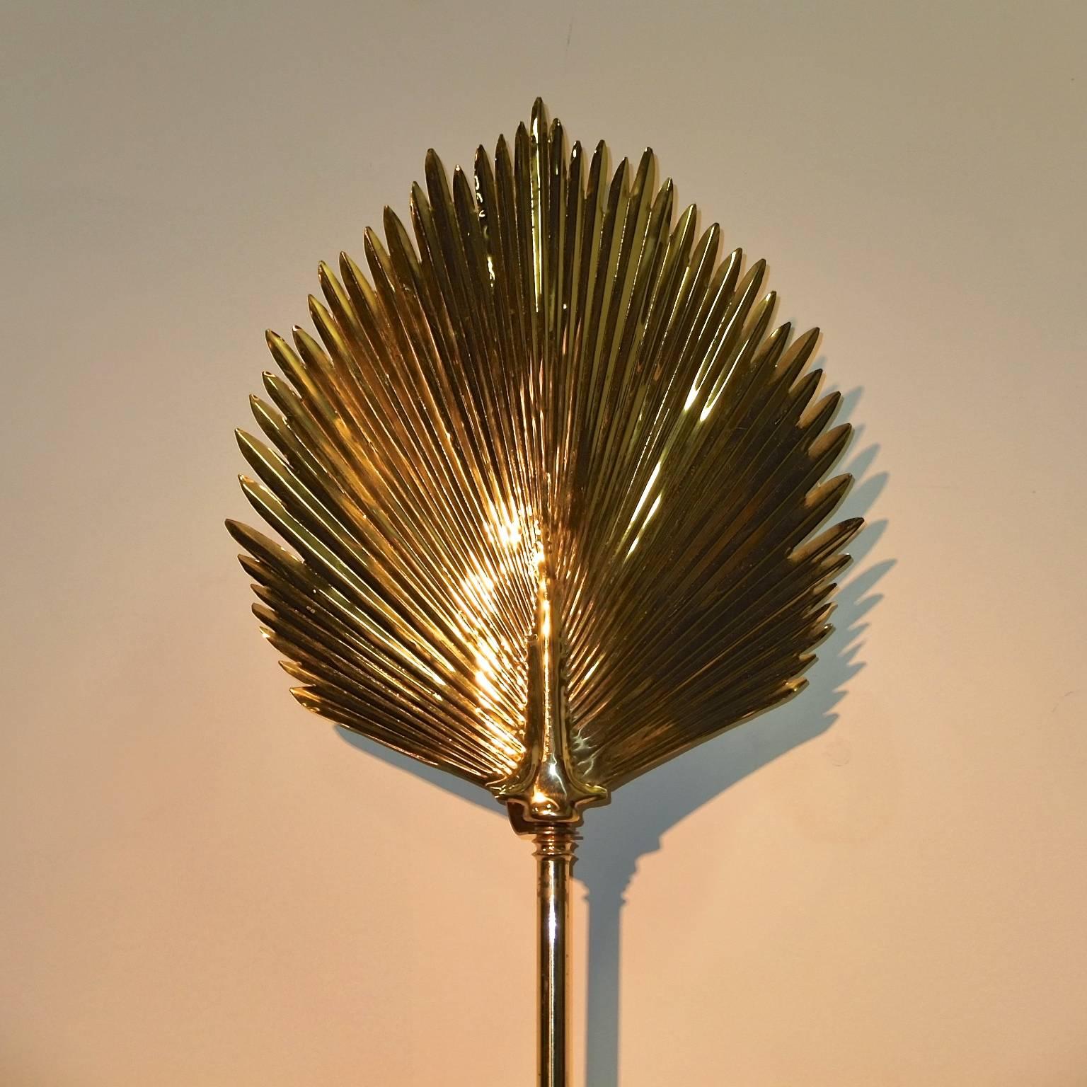 Unusual wall-mounted brass floor lamp in the style of Tommaso Barbi. Atop a long brass faux bamboo stem sits a large leaf-form brass reflector which is mounted to the wall by a rectangular brass backplate with a standard size Edison screw cap