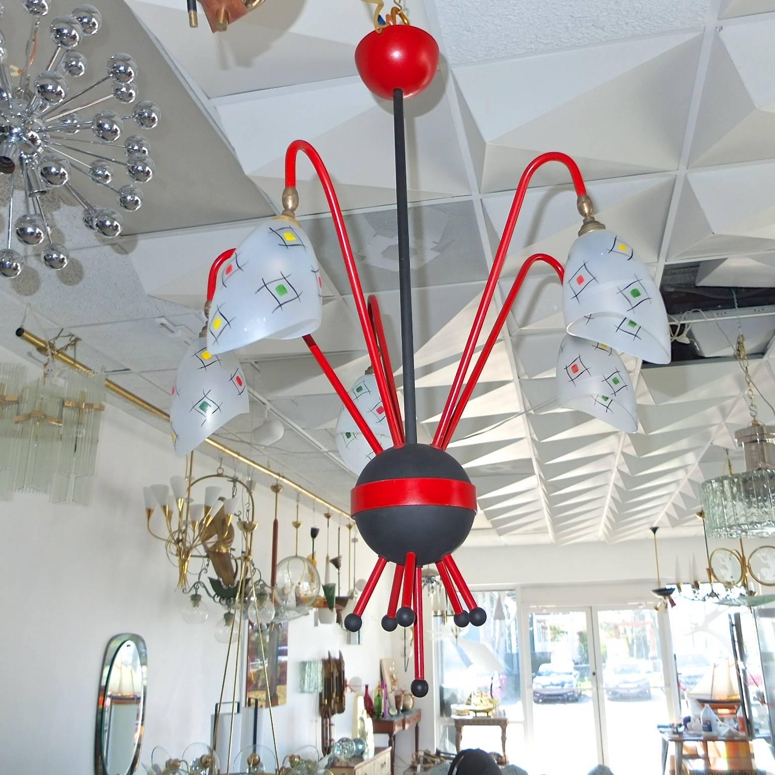 Mid-Century French chandelier, circa 1957. Red and black enameled cast aluminium 'nucleus' orb with five curved arms radiating like protons and electrons spinning around an atom. Multi-color abstract googie designs on satin glass shades which