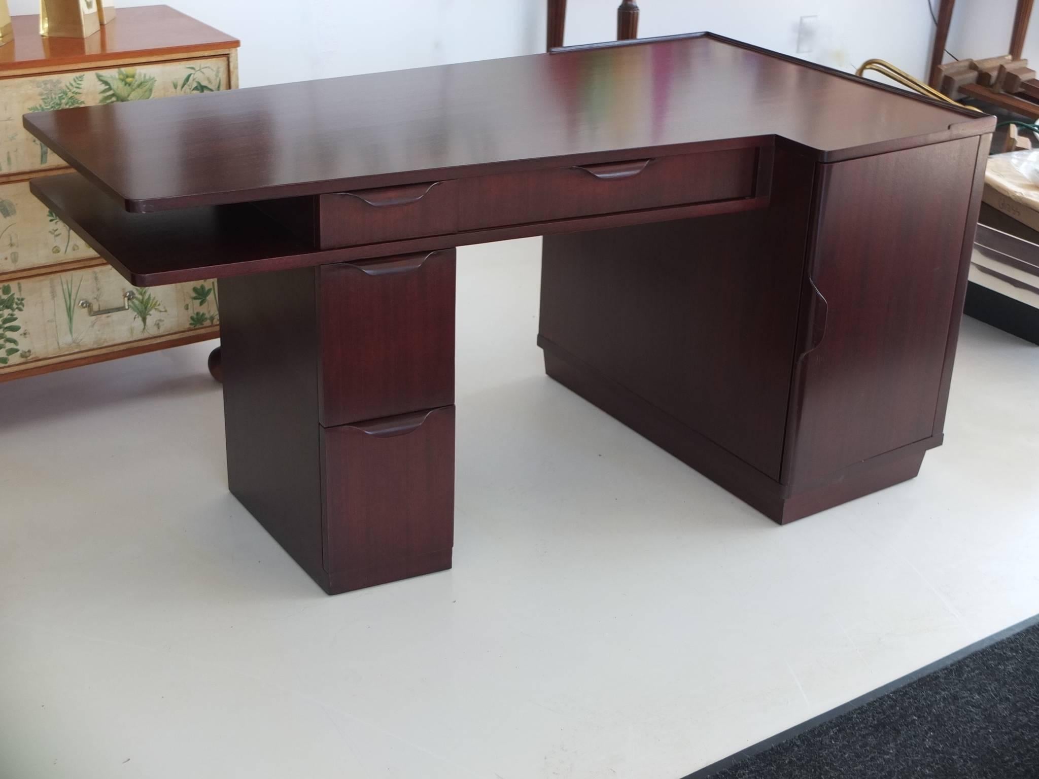 1940s trapezoidal form mahogany desk designed by Edward Wormley for directional. Open on three sides. Four drawers including typewriter tray shelf which extends and contracts via a spring mechanism. Newly restored. Excellent.

Kneehole measures: