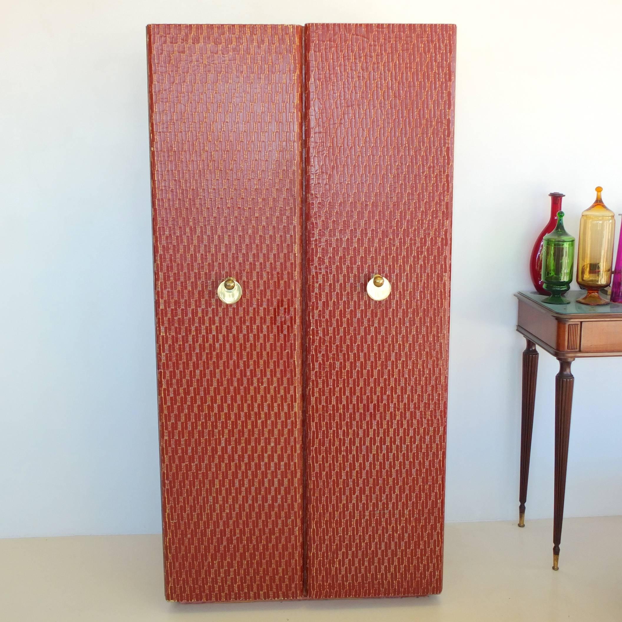 Nearly six foot standing bar cabinet wrapped in a textured cloth sealed in a dark red finish with two full length doors which open to reveal three levels the bottom for bottle storage the middle compartment, red lacquered and mirror-backed above a