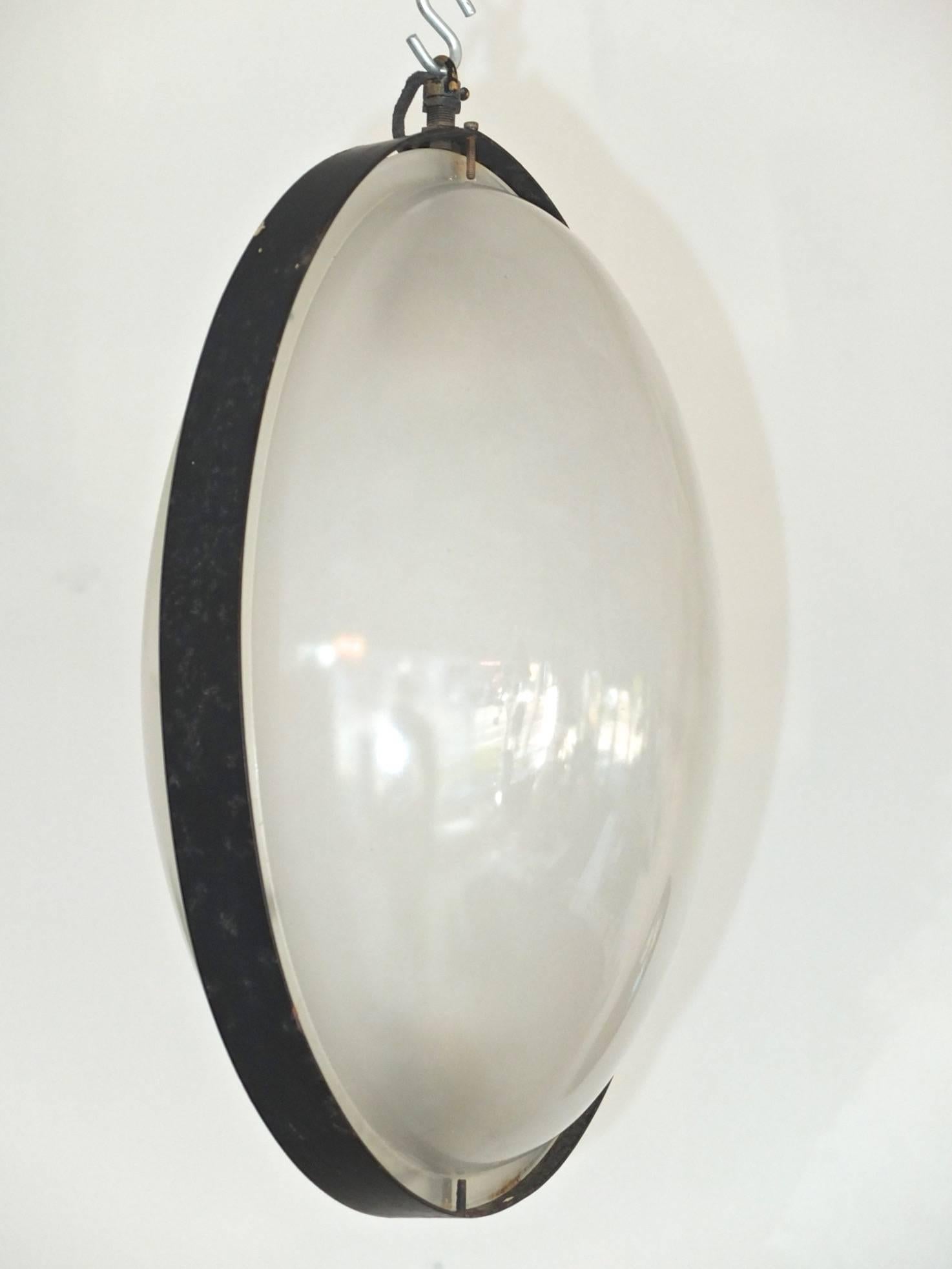 Egg shaped pendant by Stilnovo (signed). The glass lenses are smooth on the outside, lightly textured inside to present as frosted opaque. The glass is in two halves and flanged with a matte black enameled metal band. The yellow Stilnovo label is