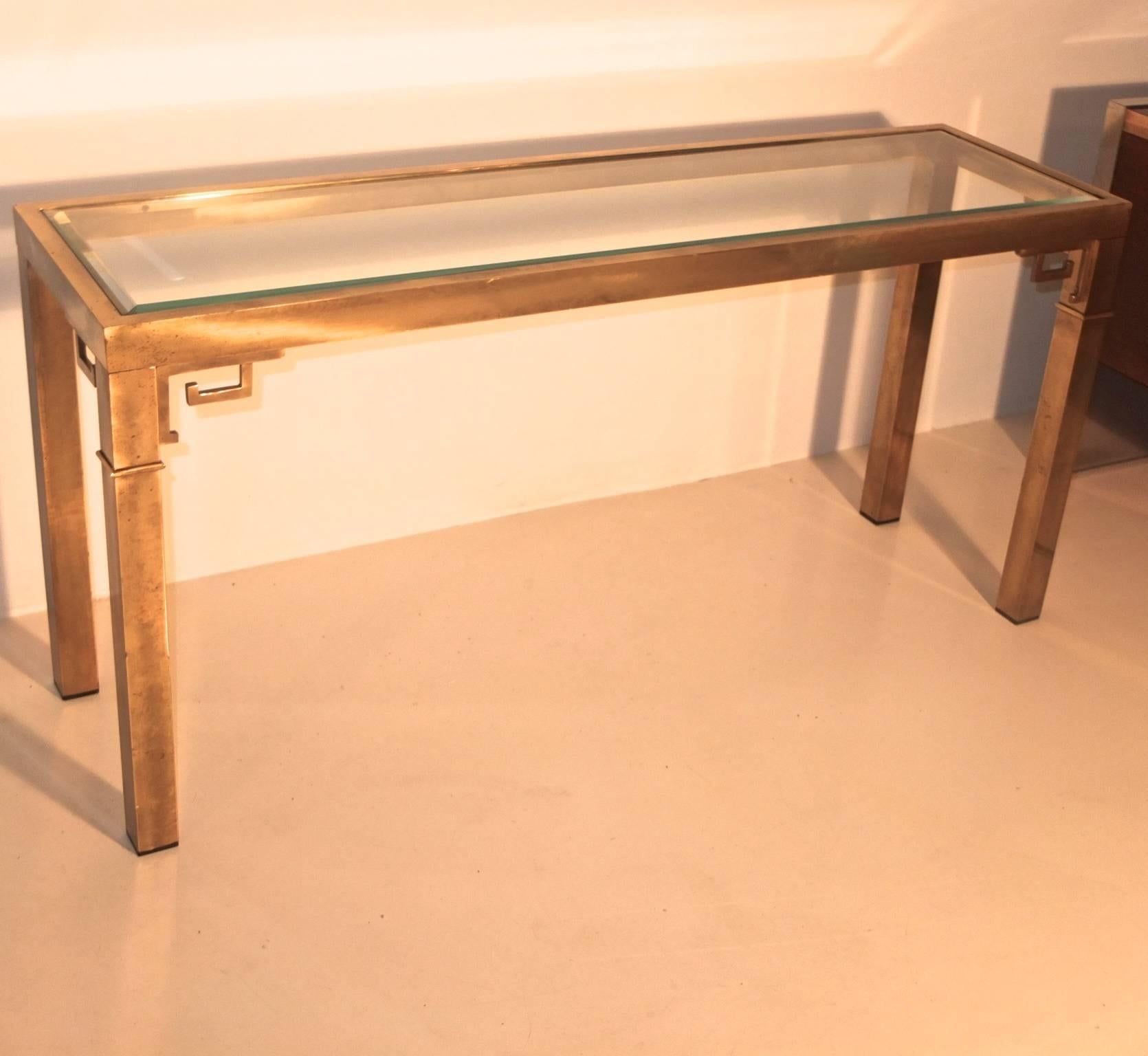Parsons form rectangular console sofa table by Mastercraft in solid brass with a clear beveled inset flush glass top and subtle greek key ornamentations.  

