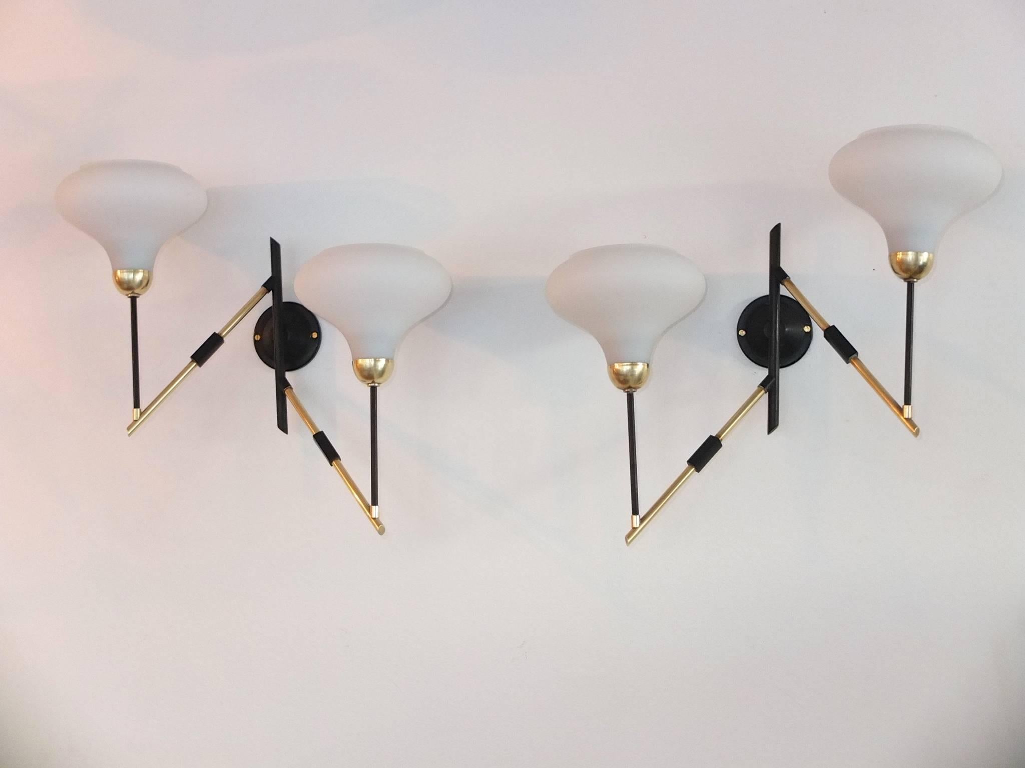 Pair of 1950s Italian sconces attributed to Stilnovo. Structure is tubular brass and black enameled metal with brass bobeche and white opaline inverted bell-form shades.

Each sconce holds two candelabra size bulbs up to 60 watts each.

We can