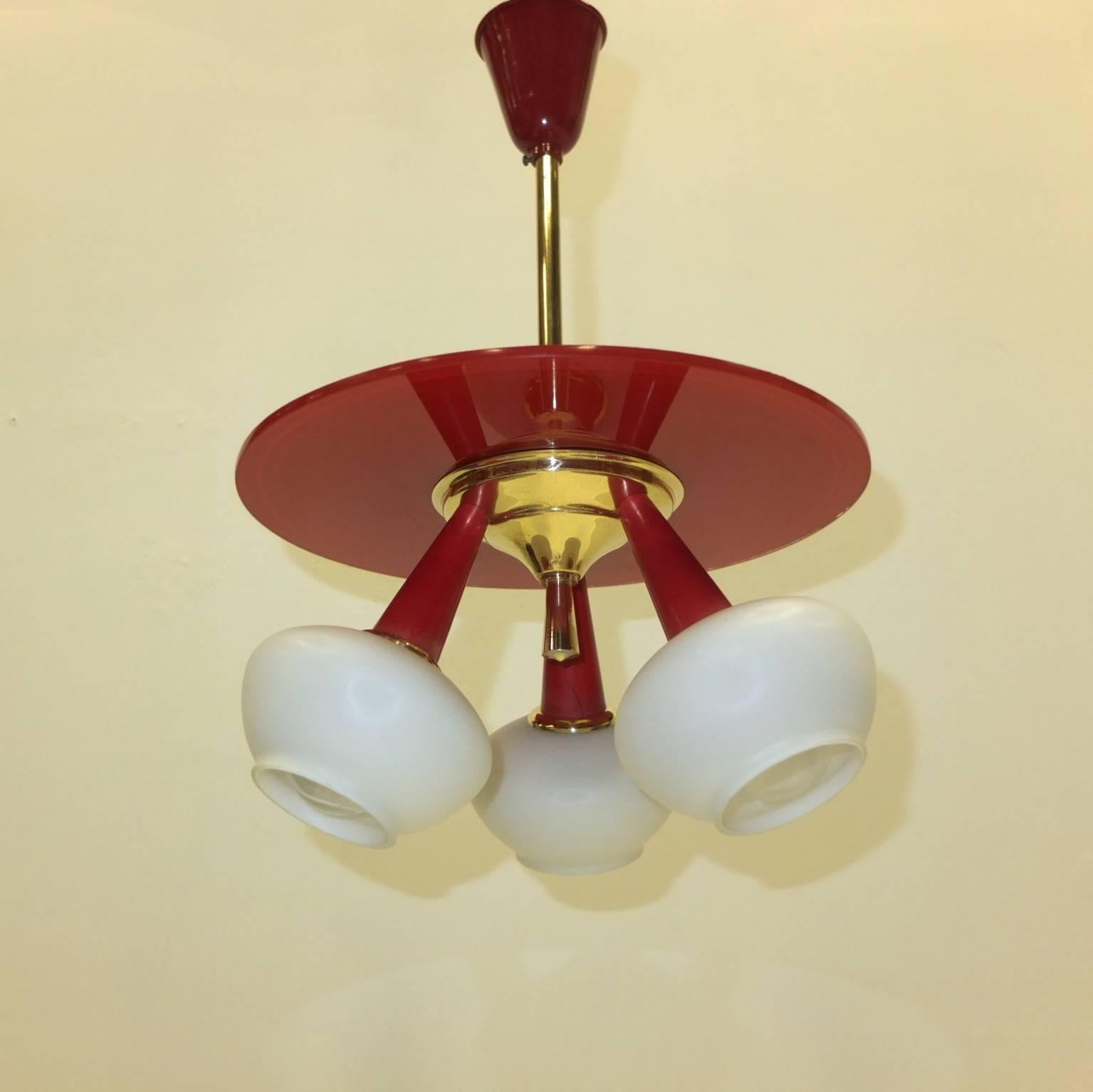 Petite 1950s Italian chandelier in the style of Arredoluce with three inverted red cones with white opaline glass globes and a reverse painted red glass disk and canopy.

We can lengthen or shorted the drop rod.

Takes three 60 watt candelabra