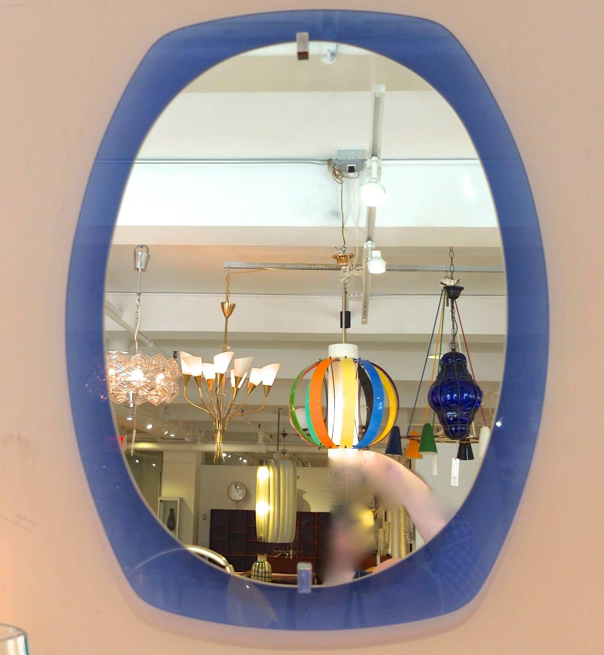 1960s Italian wall mirror by Veca. Original foil label attached to aluminum scaffold on backside. The blue glass is cushion shaped and transparent whereas the inner mirror is oval and attached by two chrome fasteners.