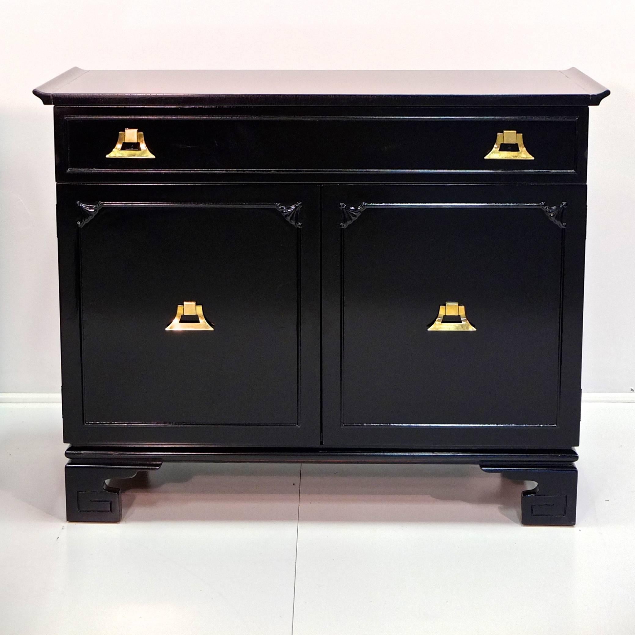 Sweet and chic pagoda form two-door, two-drawer cabinet in the style of James Mont with ming shaped feet and Asian motif detailing from the exotic modernist movement of the late 1940s early 1950s, including distinctive solid brass decorative pulls.