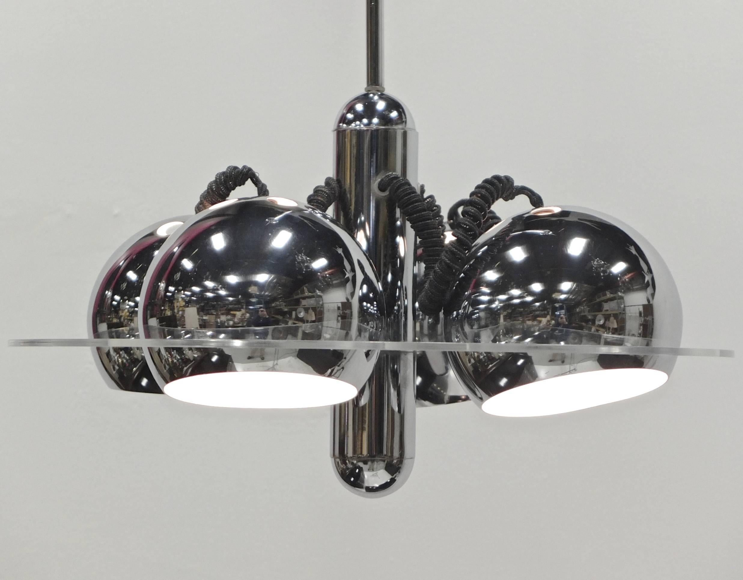 Nice chrome pendant from mid-1970s, Italy with a long chrome stem and a fatter torpedo shaped center out of which extends four lengths of black spiral cable which tethers four chrome eye ball globe shades which rest inside a round Lucite disk. The