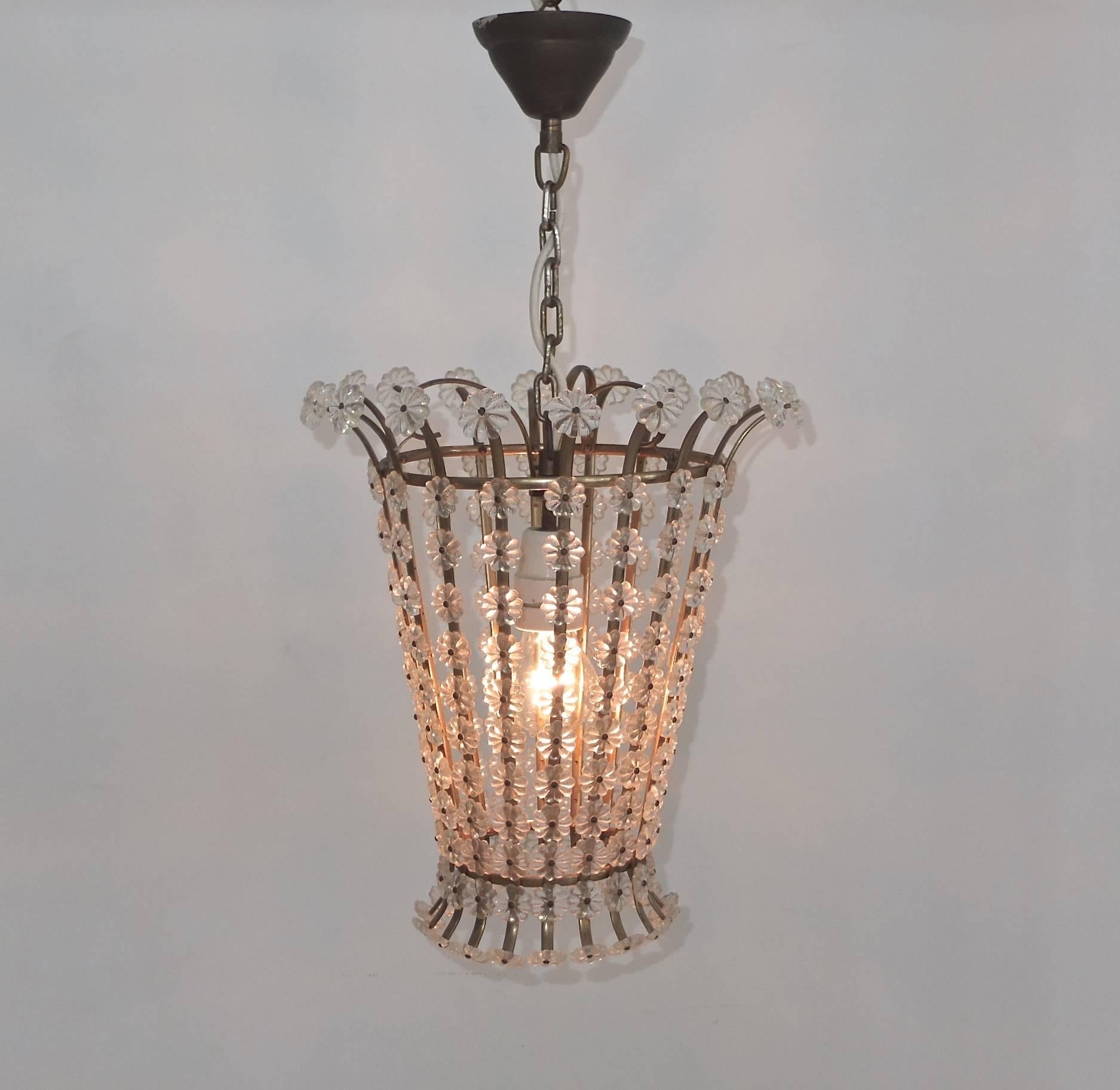 A 1950s lantern pendant from Sweden in tapered round cage form, constructed from brass hoops and straps, onto which is screwed a series acrylic crystal rosettes. A single bulb is inside the basket, standard size Edison screw up to 150 watts. Hangs