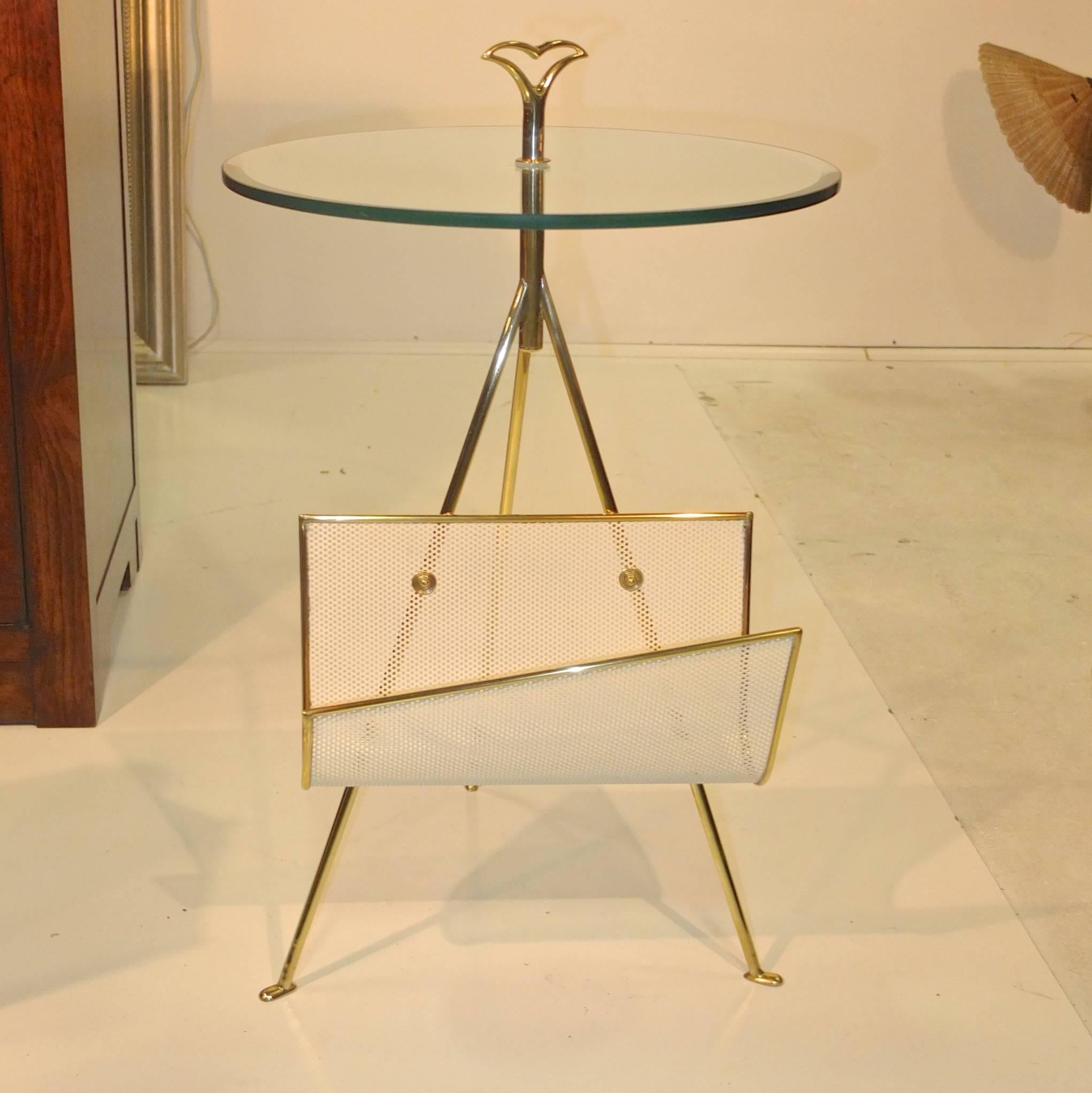 1950s Cesare Lacca attributed smoking stand with stylishly asymmetric magazine holder made of enameled perforated metal trimmed in brass, mounted on a solid brass tripod table base with a 17 inch diameter round glass beveled top secured by a