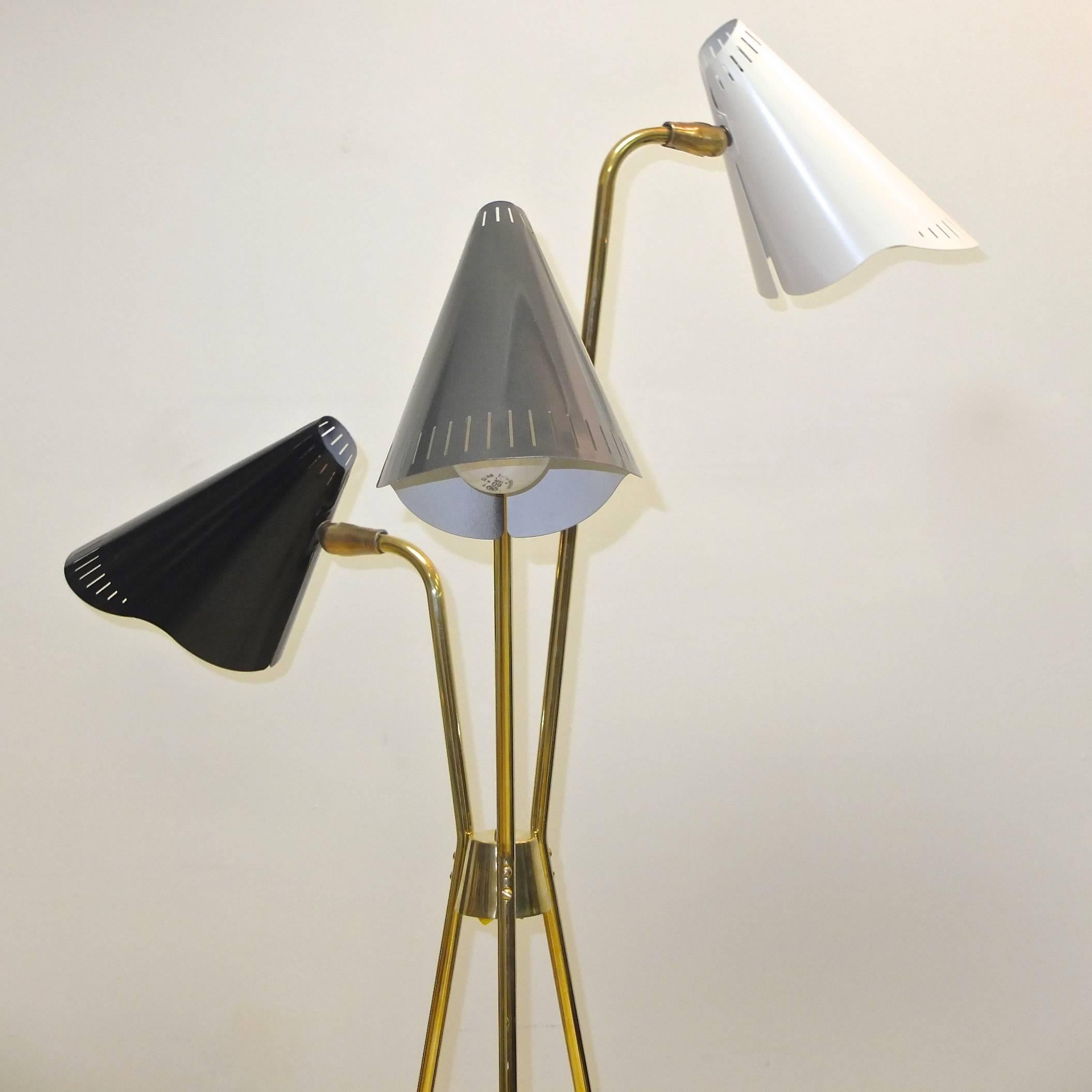 Very scarce brass tripod floor lamp with three colored cone lights designed by Gerald Thurston for Lightolier, circa 1953.

Brass switch os on the tapered brass hub where the three brass legs are secured. Switch operates one, two or all three
