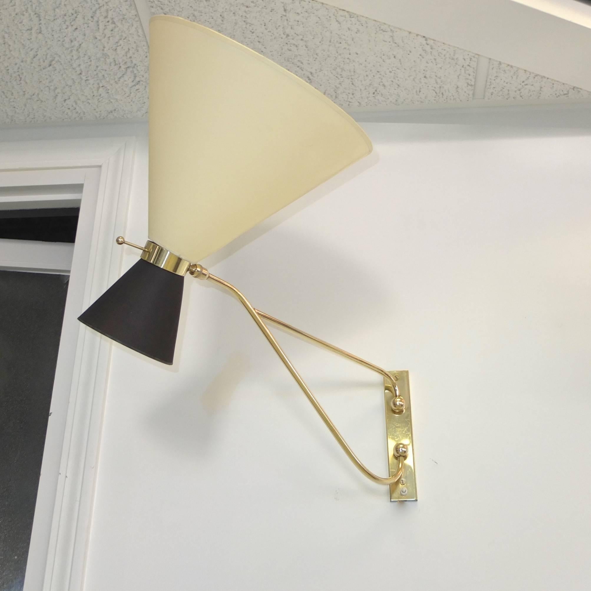 Solid brass high quality French 1950s swing arm wall lamp. Swings left to right 180 degrees. Double socket (up and down) in brass collar on a swivel joint which gives the lamp heads extensive movability.

Shown here with a two-tone diabolo shade