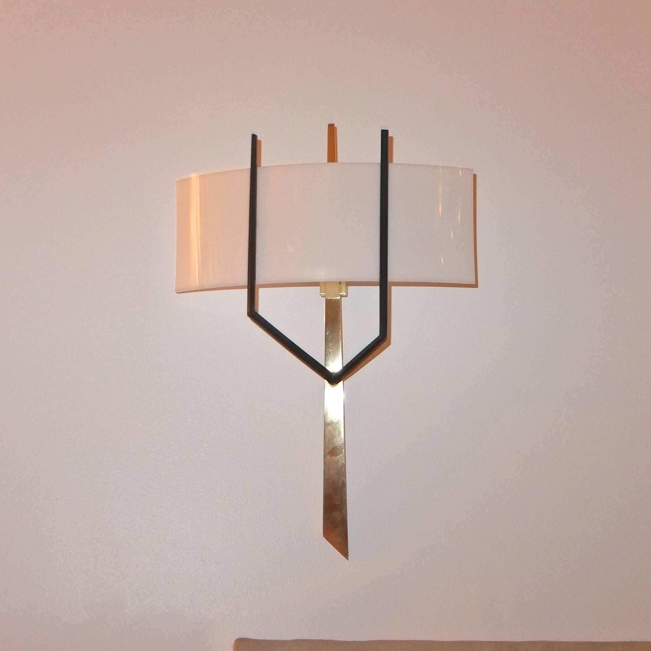 French 1950s wall-mounted lamp in the manner of Felix Agostini produced by Royal Lumiere for Maison Lunel. Organic form brass stalagmite with black oxidized forked arms supporting a curved opaque white plexiglass reflector. Two candelabra