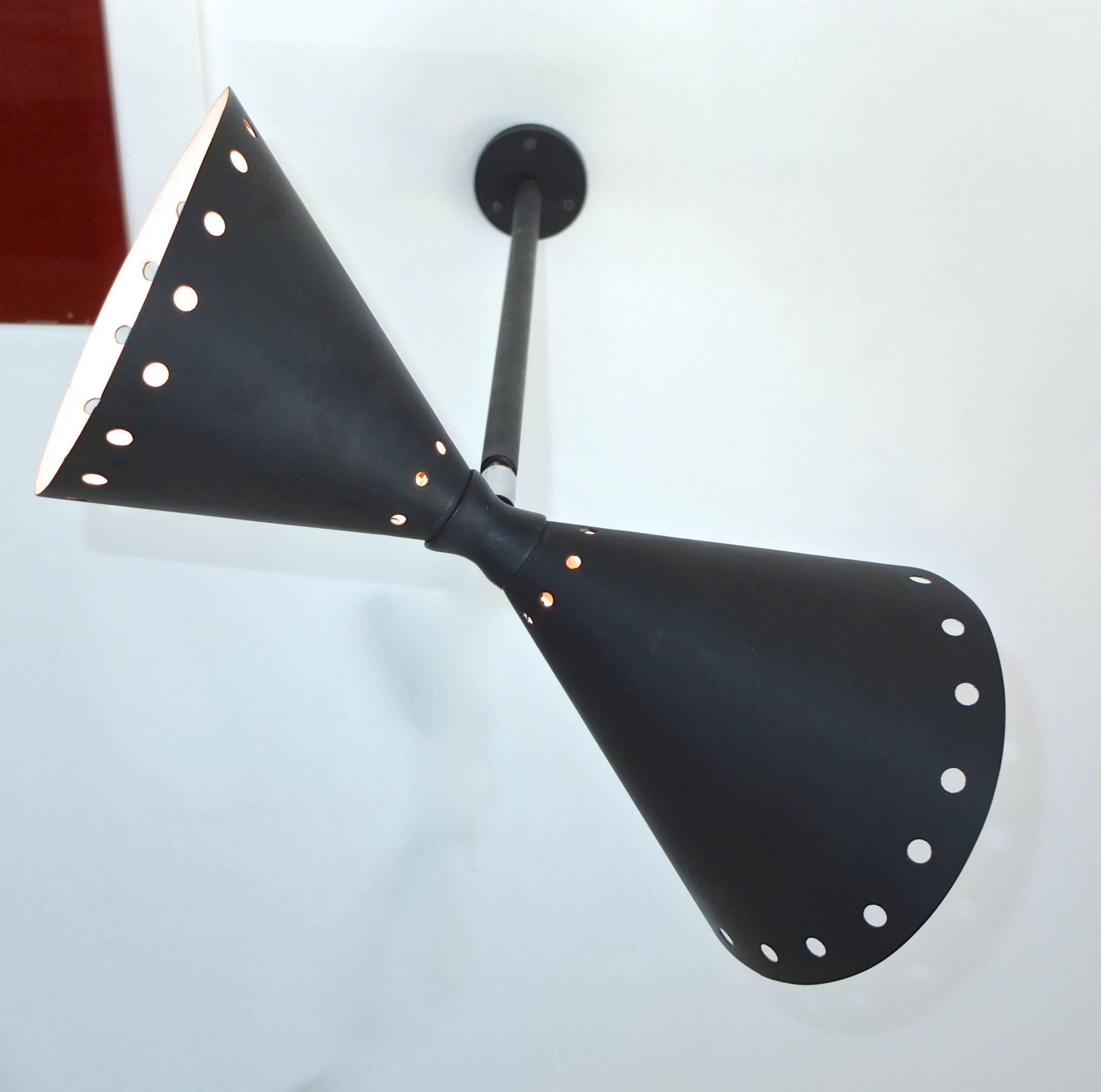Stilnovo diabolo wall sconce in matte black enameled aluminum and chrome articulating joint. Asymmetrical double cones in perforated aluminum, connected by an hourglass collar fitting. Candelabra sized bulbs in both cones up to 60 watts each.
