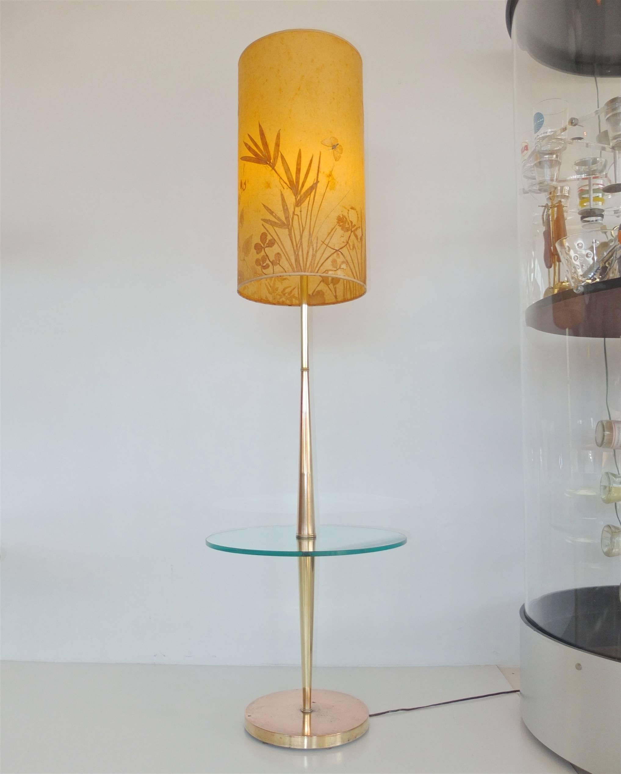 This is the sexiest one of these lamp tables I've ever seen. Note the quality of the double inverted and elongated tapered cones which form the stem. Where they intersect is the round glass disk table surface. The weighted base is made of copper.