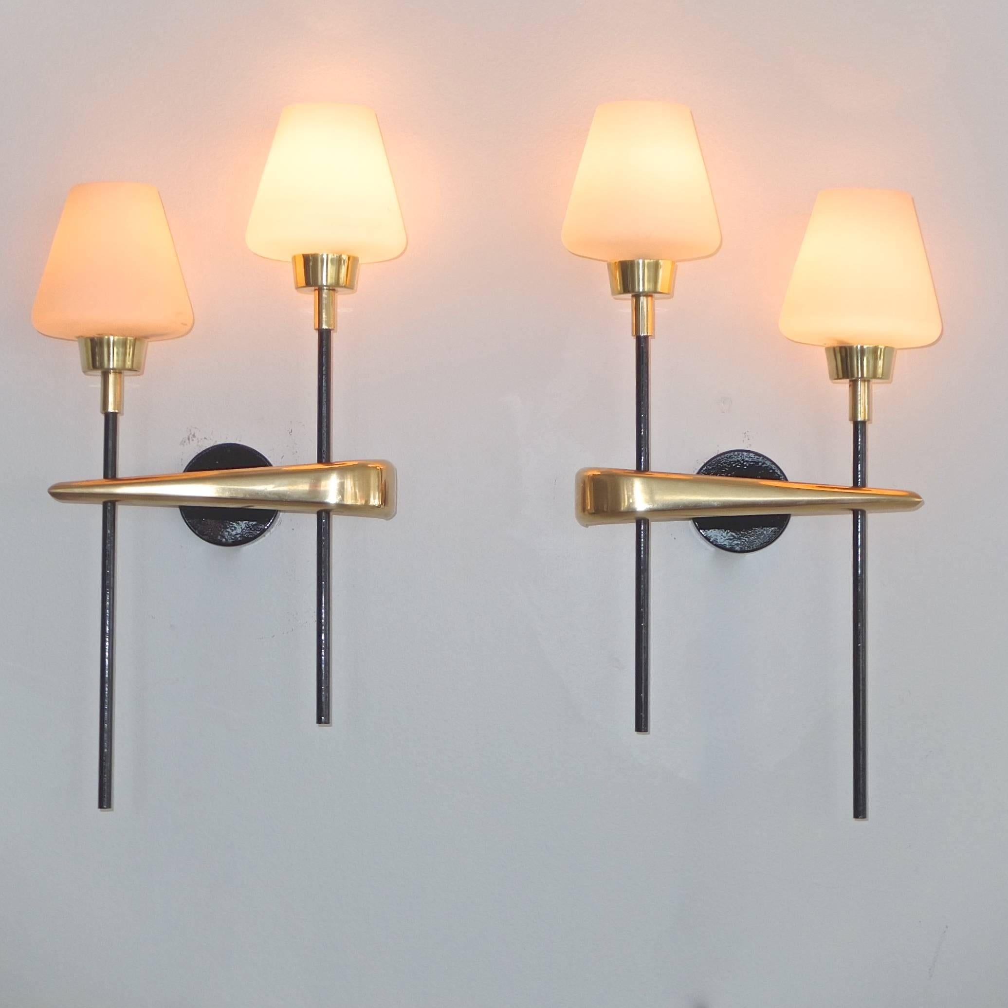 
Pair of French, 1950s wall-mounted sconces from Maison Arlus each with two upright lights (ascending and descending like musical notes). Each light has a single candelabra socket and a satin white opaline cased glass conical shade. Very heavy and