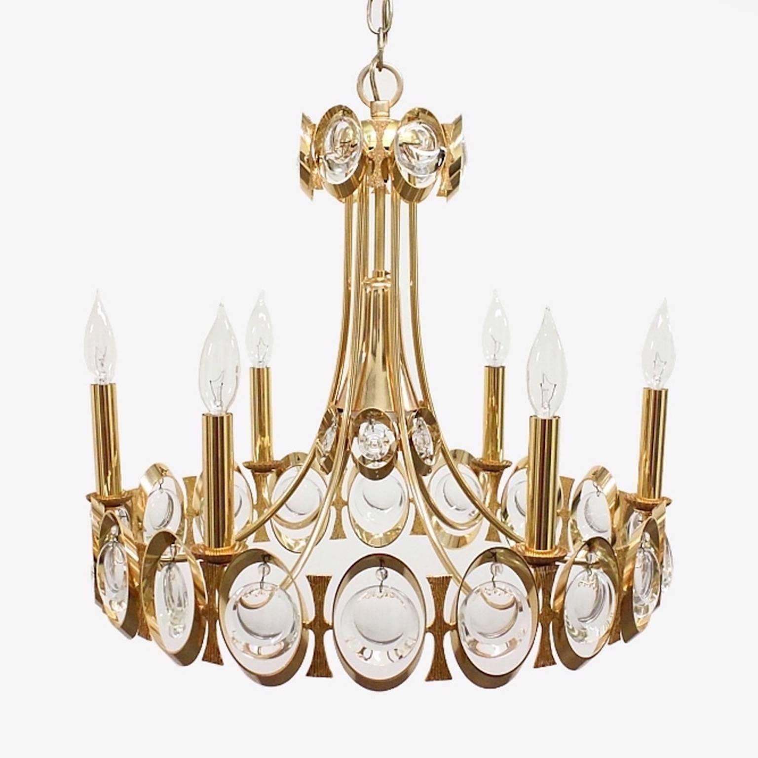 Lampadario vintage glamour degli anni '60 di Palwa, Germania. Forma rotonda a venturi con anelli ovali in ottone dorato interconnessi in cui penzolano i cristalli prismatici a lente ottica molata. 
Questo lampadario è dotato di sei luci a candela