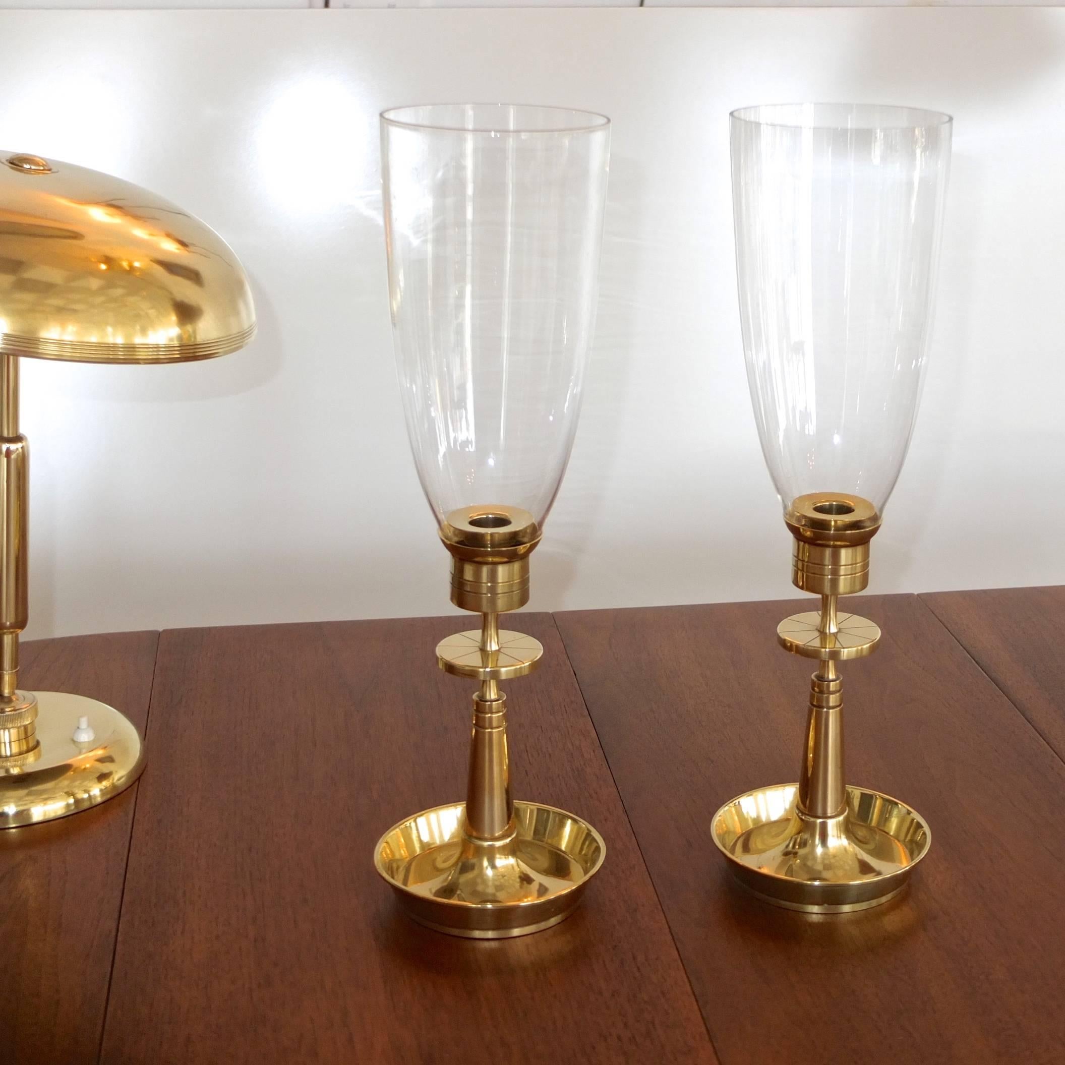 We actually have two pairs available. Price shown is for one pair.

Pair of Tommi Parzinger designed brass candlesticks for Dorlyn Silversmiths circa 1955 with clear glass hurricane shades.

Dimensions for each candleholder are 5.5