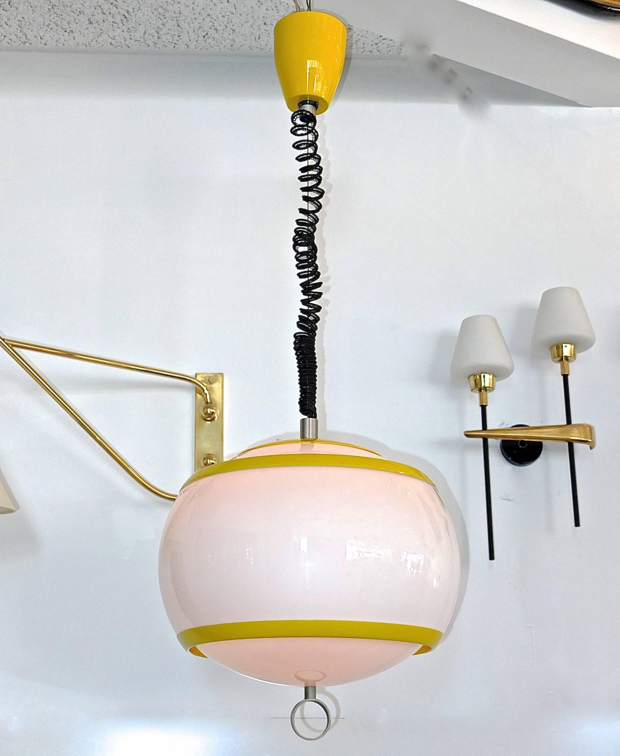 Cheerful vintage white acrylic pendant globe light with enameled metal yellow banding and canopy by Stilux Milano. Aluminum ring finial and spiral telephone cord style suspension cable. On/Off switch on top of globe.
