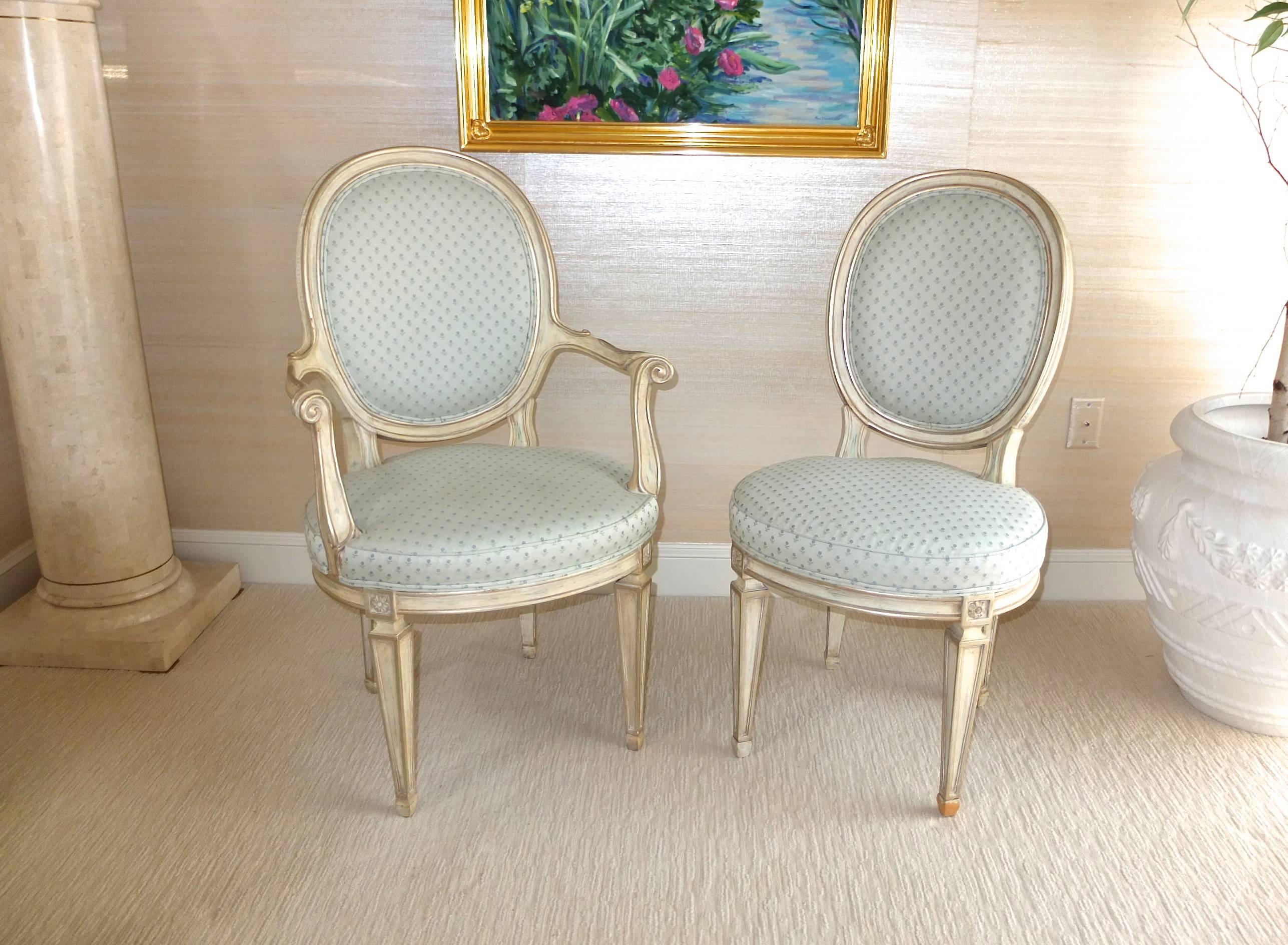 A mixed pair (one with arms) of Louis XV style oval back chairs paint finished in silver cream with Brunschwig & Fils cotton and silk small patterned leaf design in a pale aqua marine color upholstery. 
Dimensions of chair without arms is: 37.5