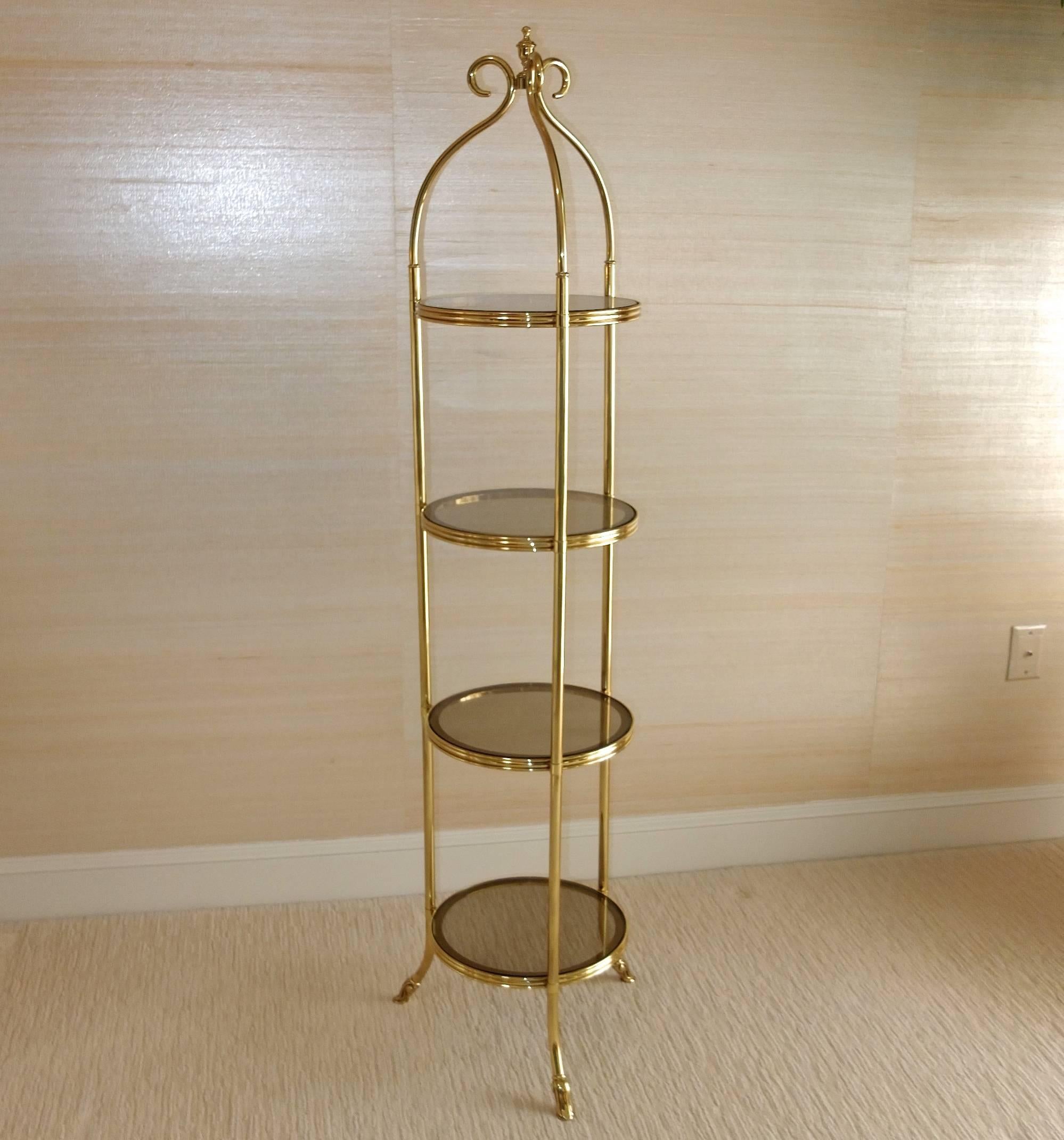 High quality brass three-legged etagere tower with four 12 inch round brass and smoked glass shelves. 5 feet tall. Produced by La Barge, circa late 1970s.

Versatile and functional. Perfect for a powder room.

Brass is brightly polished with no
