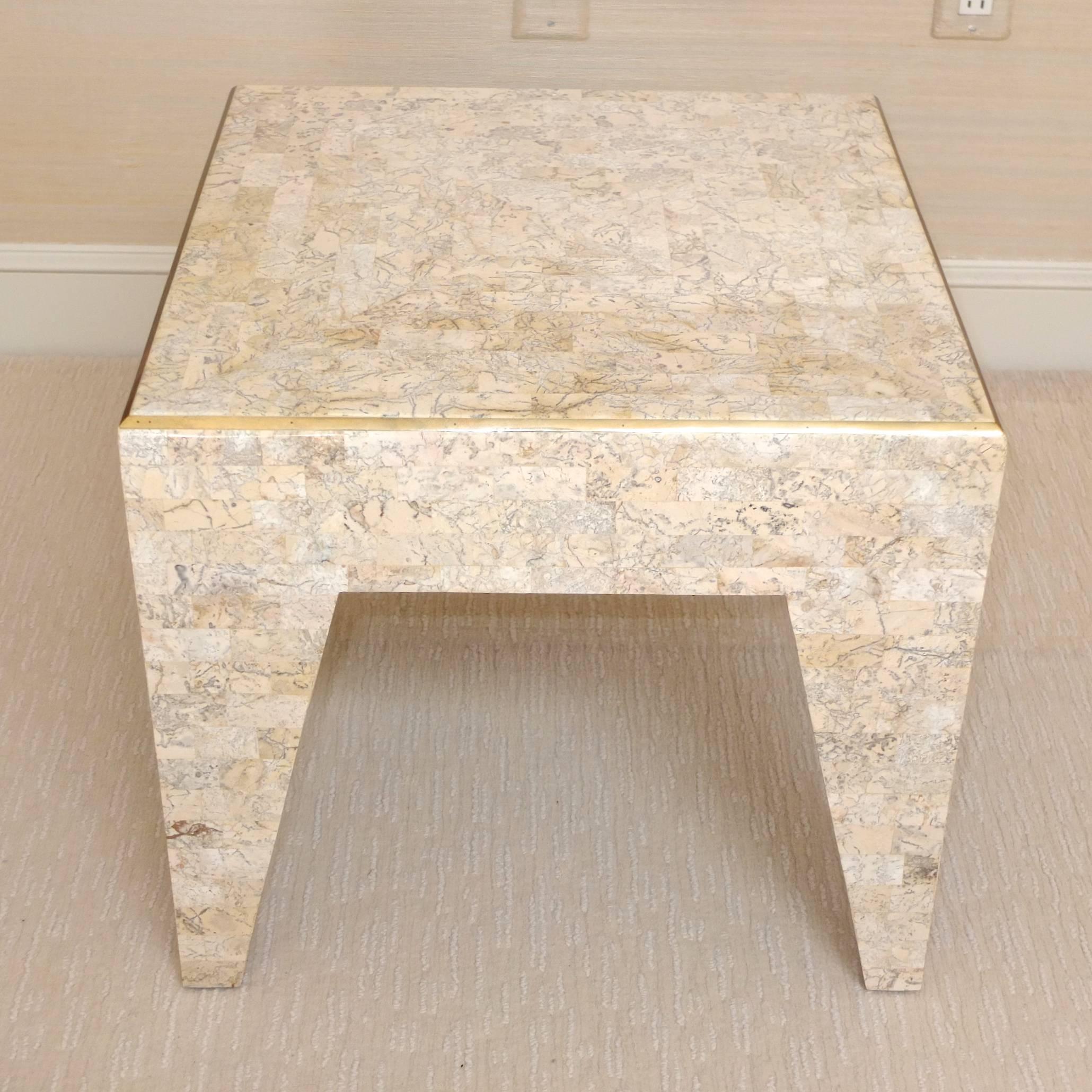 Versatile occasional table by Maitland Smith in tessellated fossil stone and brass inlay over wood structure. Tapered 3-D geometric pyramidal legs. Engraved brass label on underside.  Excellent condition.