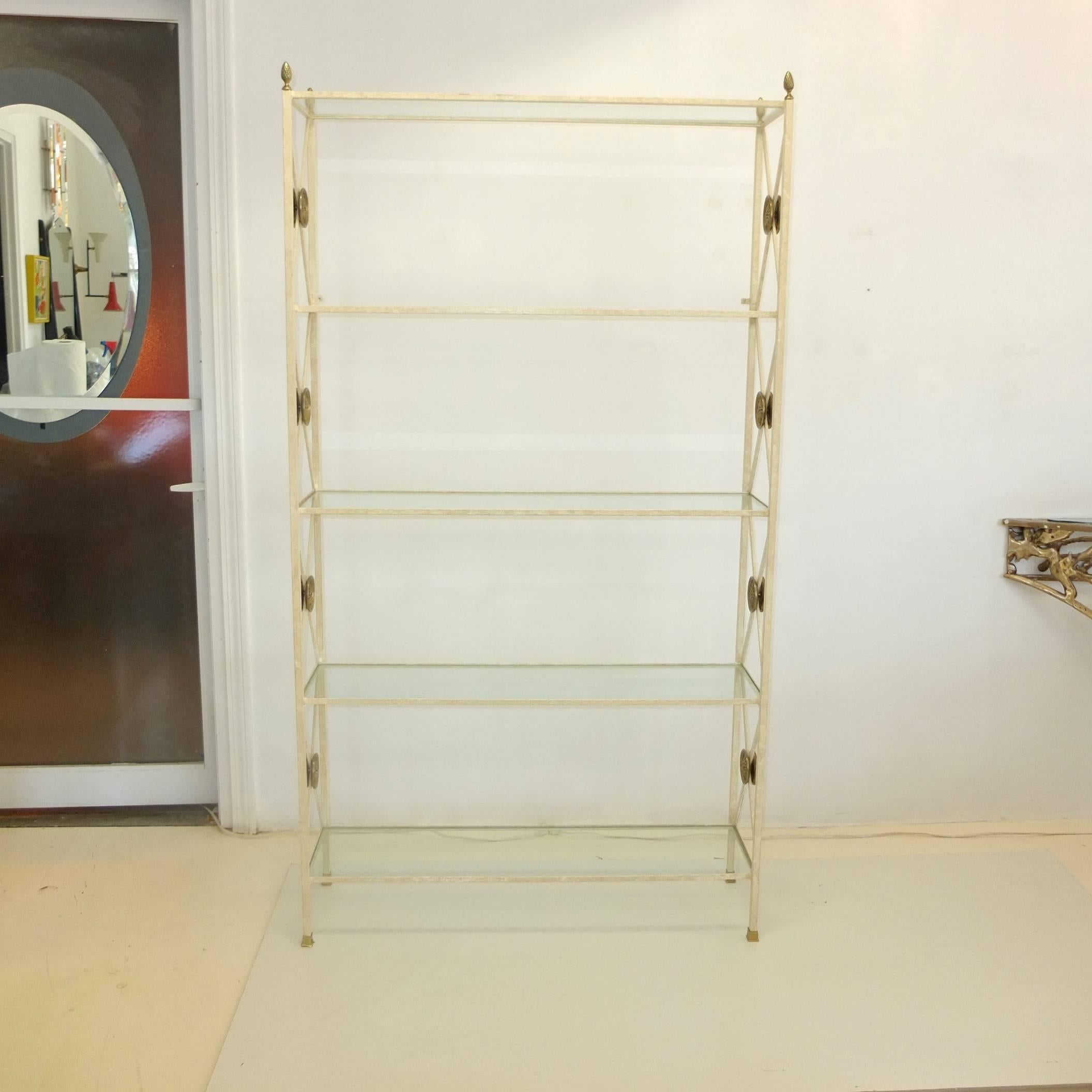 Hecha a medida, hacia 1980, por un herrero de Boston. Estantería de hierro soldado en forma de directorio, con cuatro estantes de cristal encastrados, flanqueados por soportes en forma de X con grandes adornos redondos de latón. Cuatro remates de