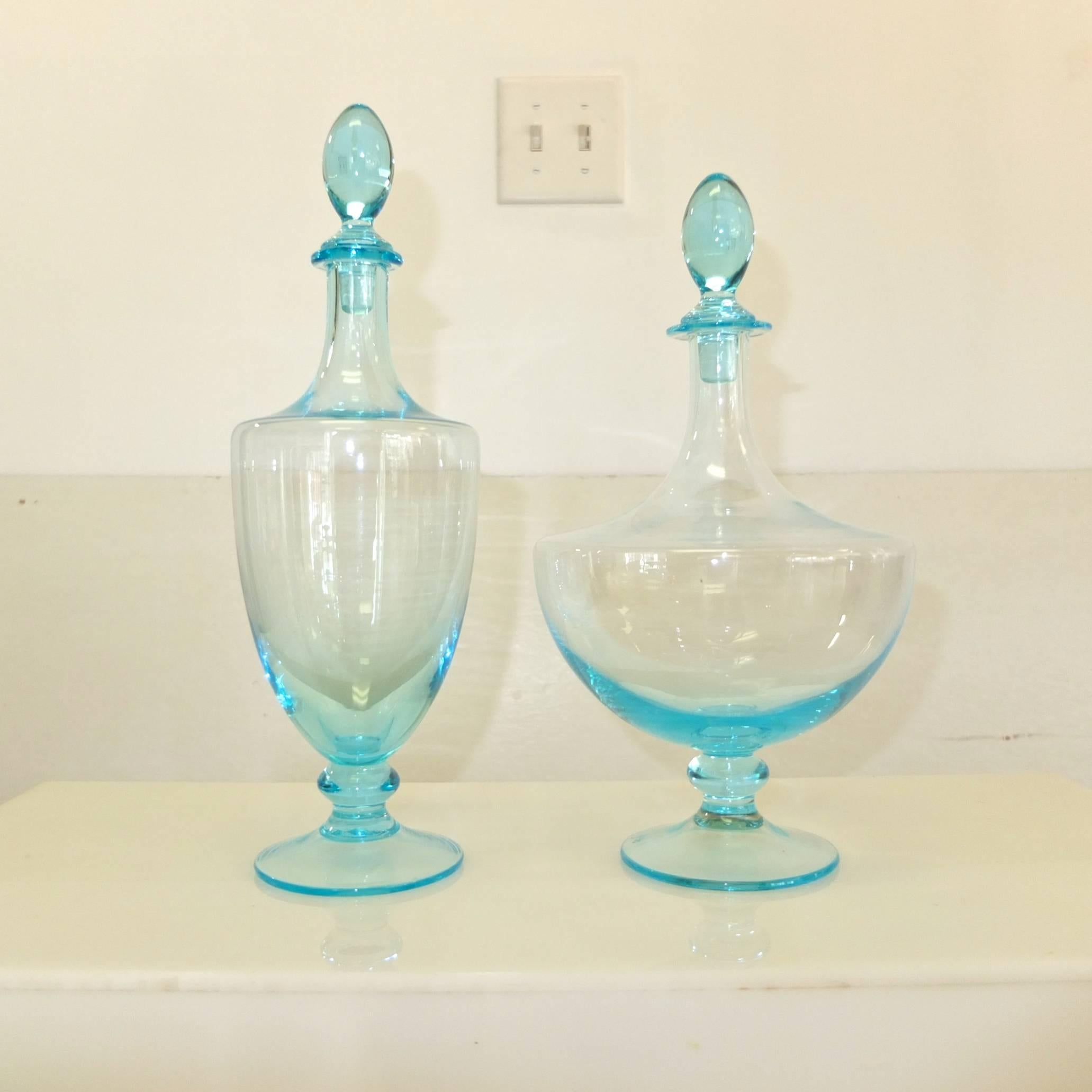 Stunning classical form handblown blue glass decanters. Signed and dated 1990 but I can't decipher the signature. See image 8. 

The crystal clear ice blue color is arresting.

The forms are stylized amphora footed bottle vessels with