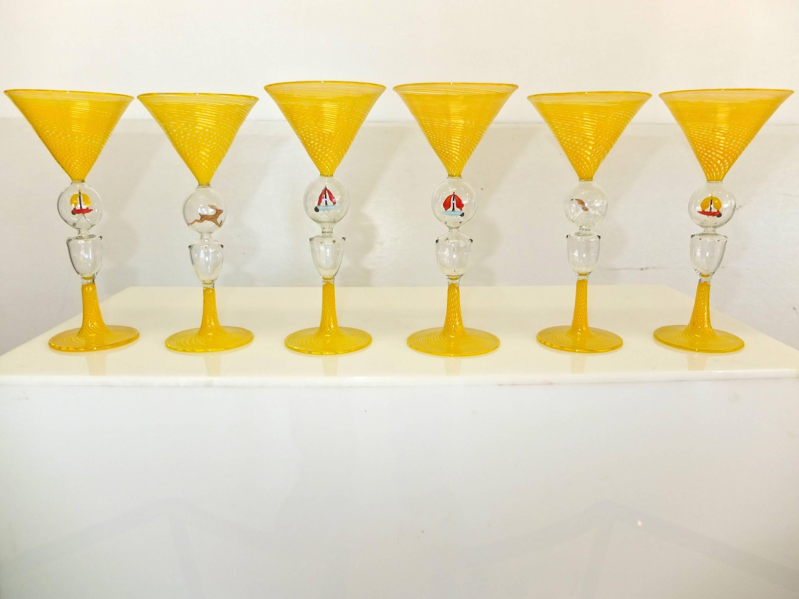 Set of six yellow swirl Bimini Werkstatte martini glasses, each having a double knop stem, the upper enclosing a figure (hound dog, hare and four which appear to be a sailboat), the lower of triangular form with drop prunts.