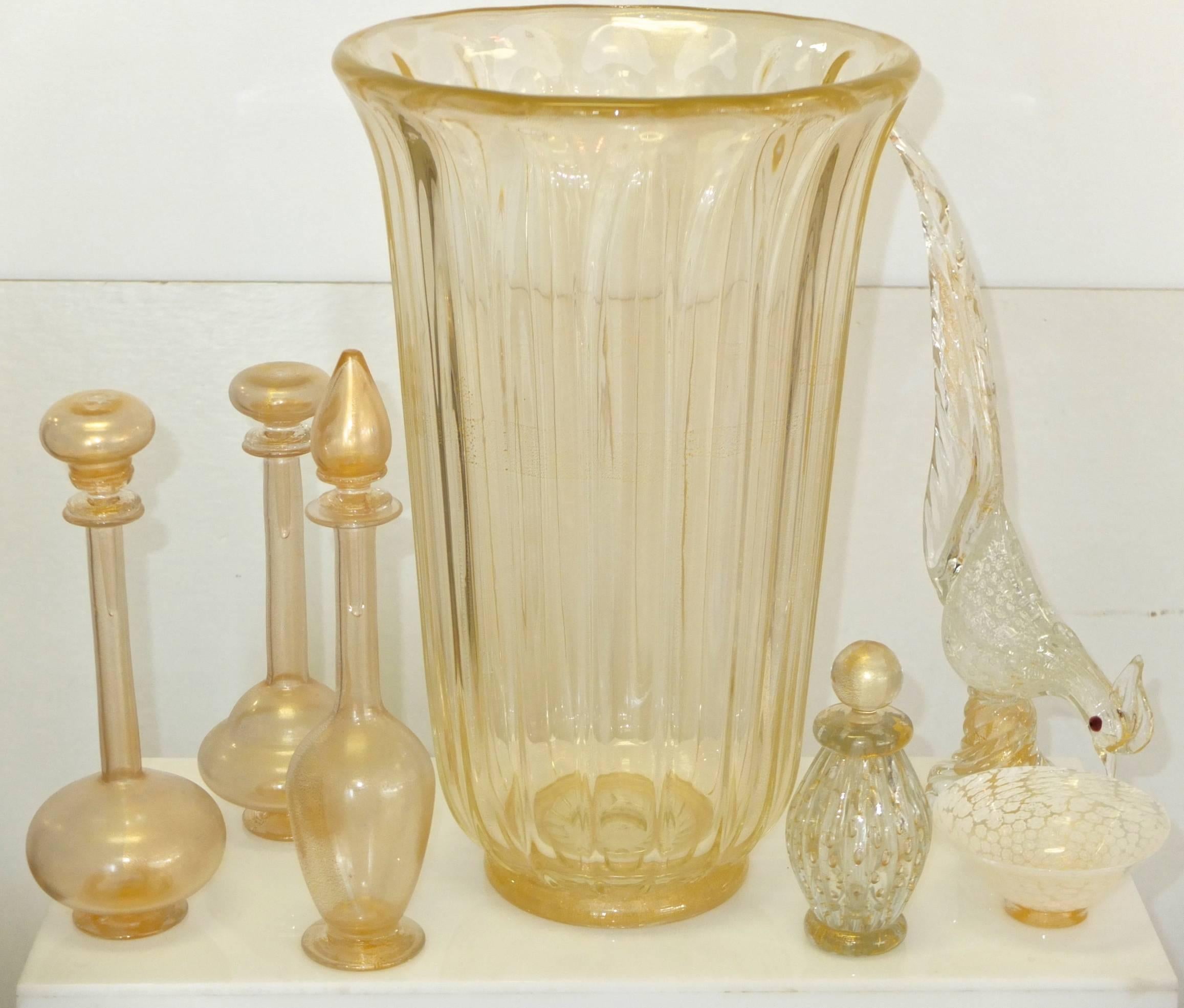 Hier wird eine stilvolle Kollektion von sechs Gegenständen für Madame's Boudoir präsentiert: vier signierte Parfümflaschen aus Muranoglas mit Stopfen, eine Schale mit Fuß und eine elegante Vogelfigur, alle mit eingelassenen Blasen und Goldflecken im