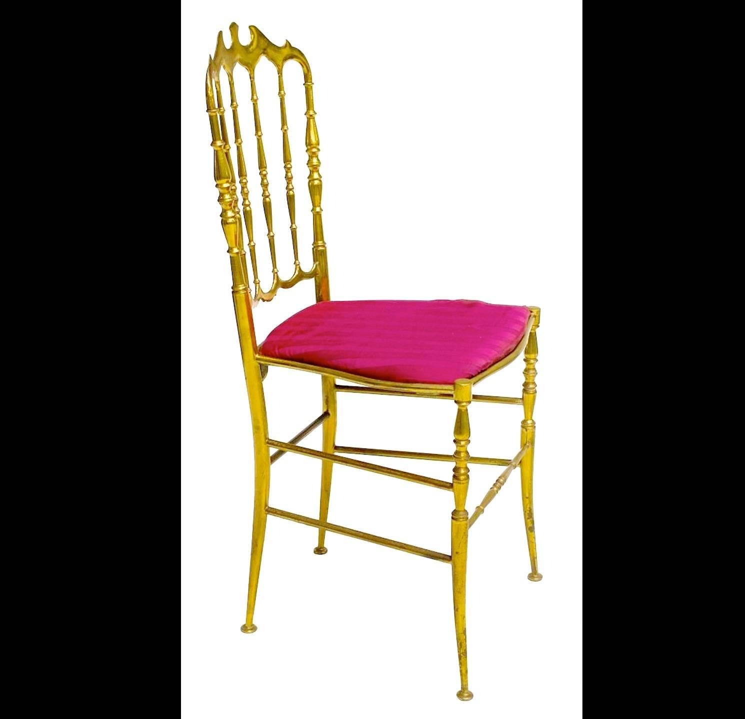 Pair of solid brass Chiavari ballroom chairs, Italy, c. 1960 with gilt brass frame, red upholstered seat, over tapered legs joined by brass stretchers.

This is the gold standard in chic! Solid polished brass 1960's Chiavari chairs with dainty splay