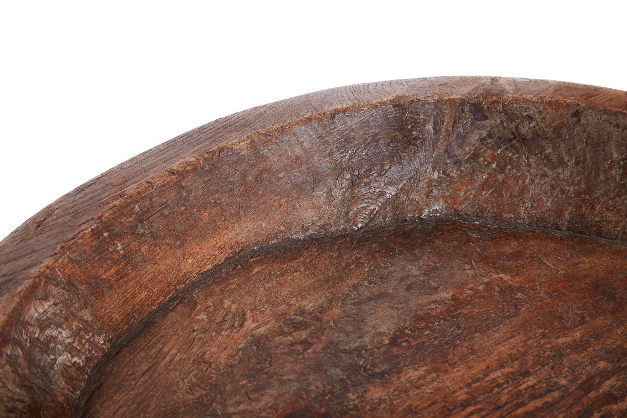 Early 20th century hand-carved massive wooden bowl from Indonesia 
This Hefty and handsome wooden bowl is large and shallow 
Patina is wonderful and the piece works empty as shown or filled with any number of decorative things.