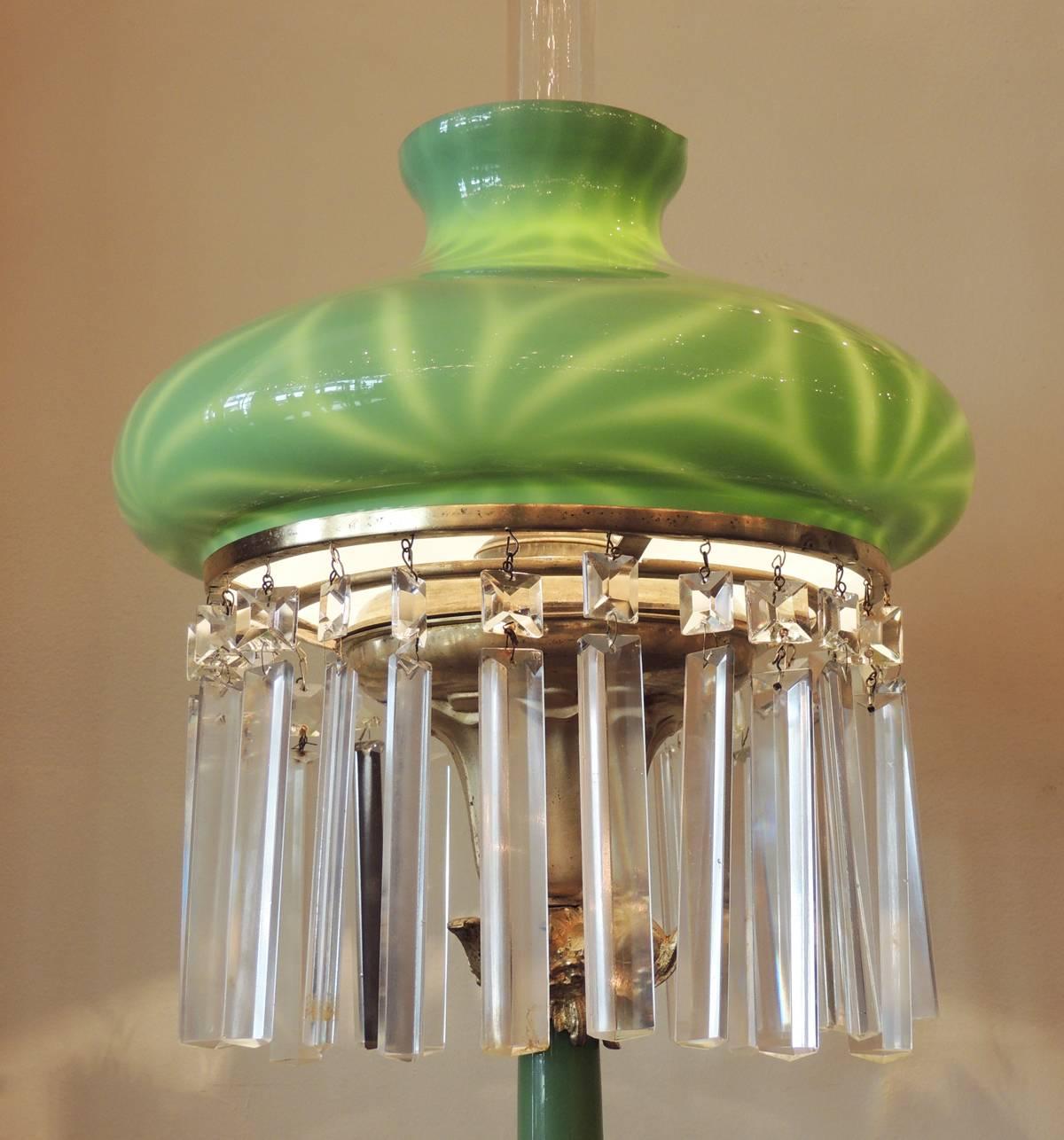 This magnificent lamp was created in the early half of the 20th century, circa 1900. This fixture features an art glass shade in the unusual tam-o-shanter form with pinwheel design. The shade has long hanging crystal prisms that surround tulip shape