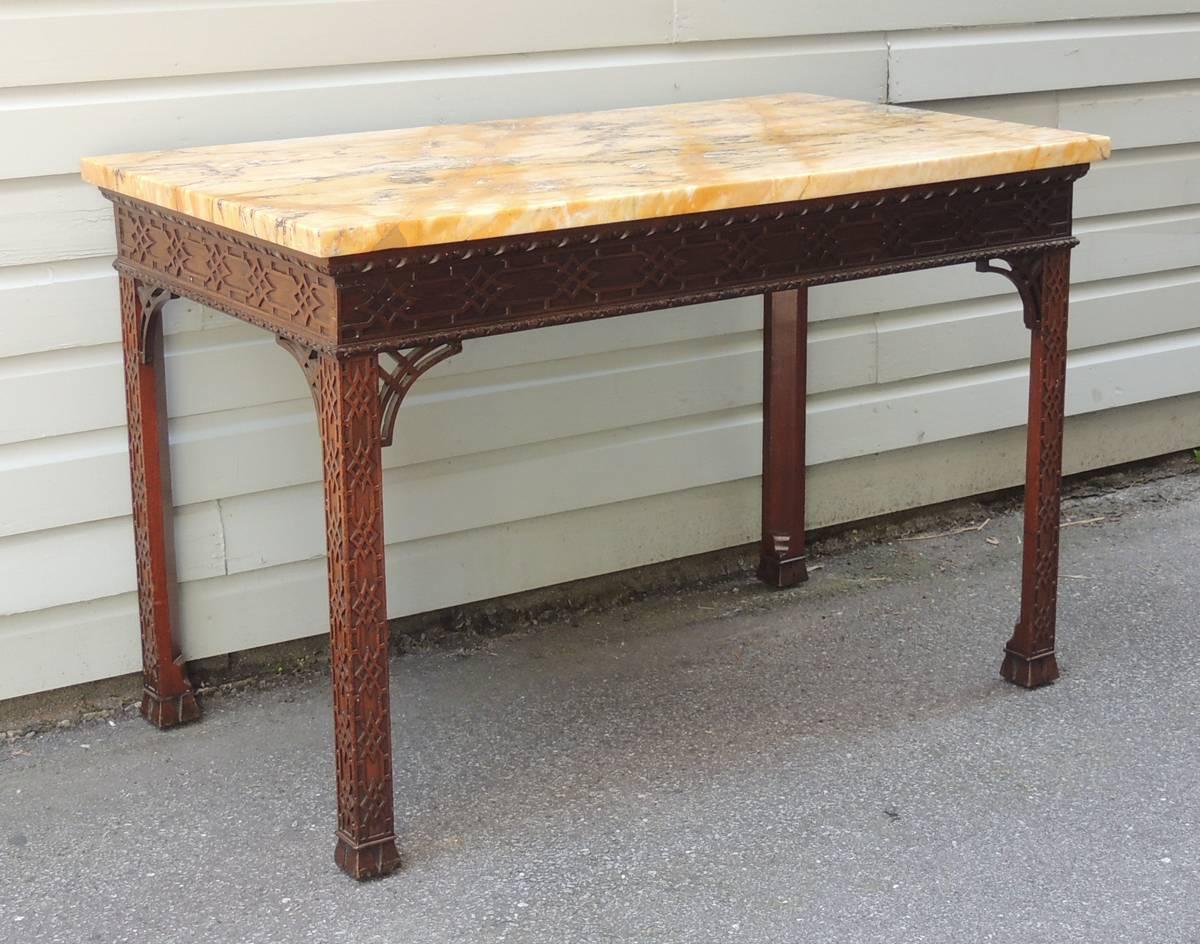 This table was made in England, circa 1760, and was created in the Chinese Chippendale taste. This table features a thick golden hued marble slab top. The skirt of the table has egg and dart border surmounted over diamond chinoiserie blind fretwork