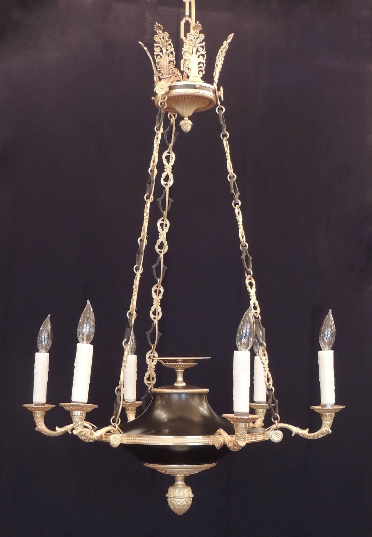 This Empire chandelier was created in France in the early-19th century, circa 1820, and has a crown with six palmettes and three suspending gold and black chains to support the body. The main body of the fixture has a center bronze urn, six arms and