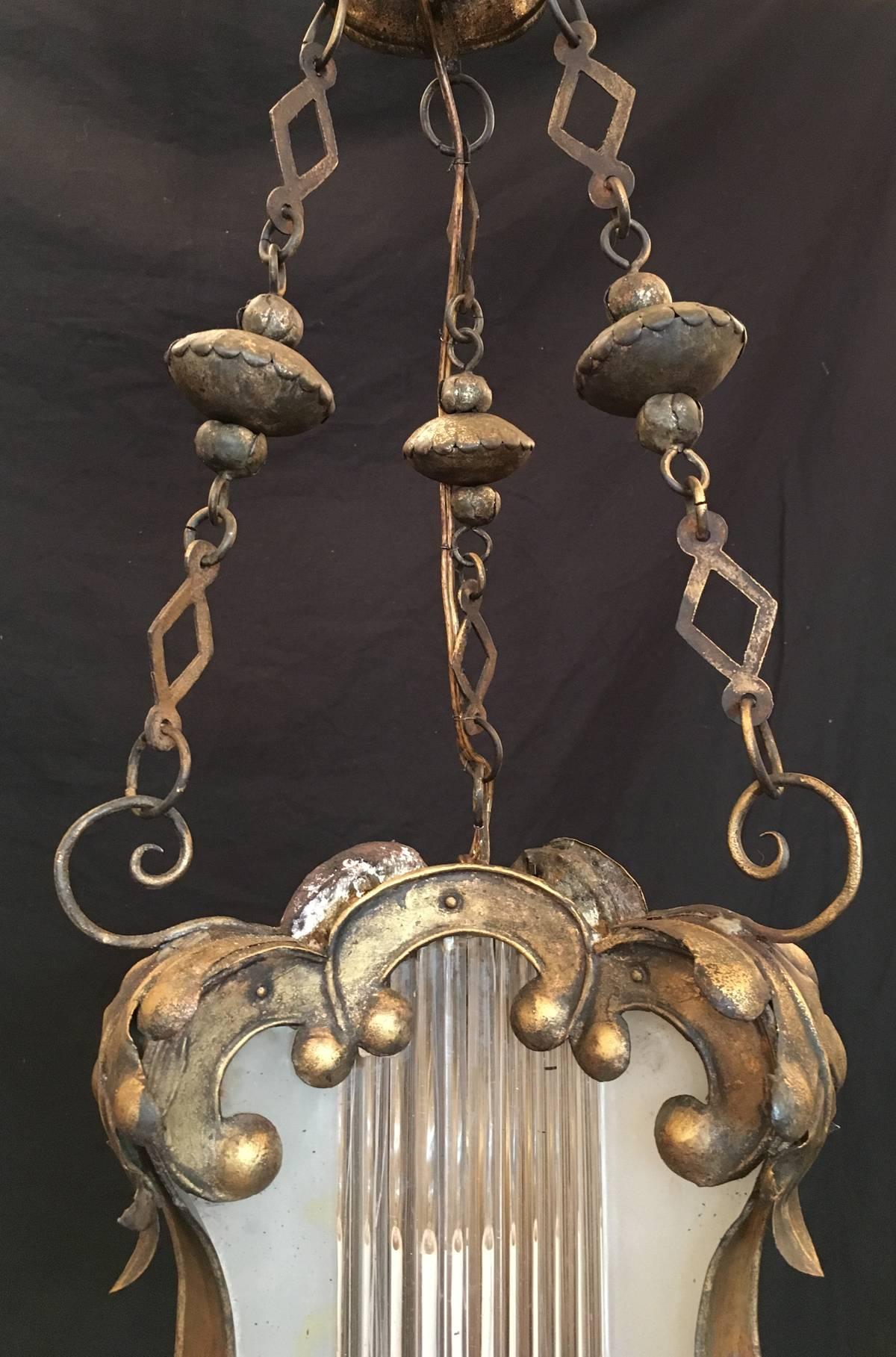 Cette lanterne baroque a été fabriquée à Venise, en Italie, au XVIIIe siècle, vers 1760, et présente un corps en étain doré couvert de volutes et de motifs floraux. Le centre en verre dépoli contient des tiges en verre soufflé vénitien et était à