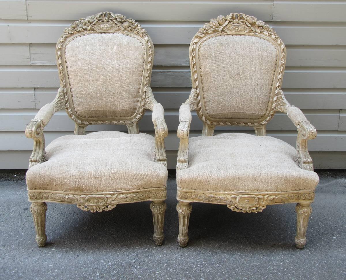 Pair of matching fauteuil chairs with classical French carvings, featuring ribbons and flowers, and new upholstery.