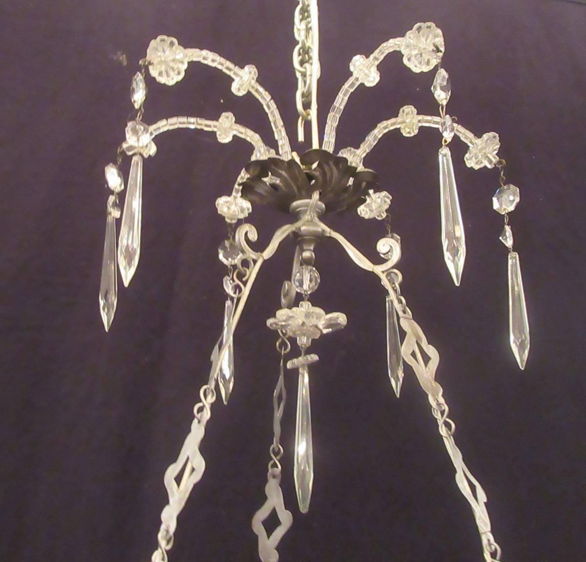 This chandelier was made in Italy in the early-19th century, circa 1820. This chandelier has a crown with crystal beads and rosettes suspended by three brass chains and six arms with crystal flowers and prisms. The chandelier was originally candle