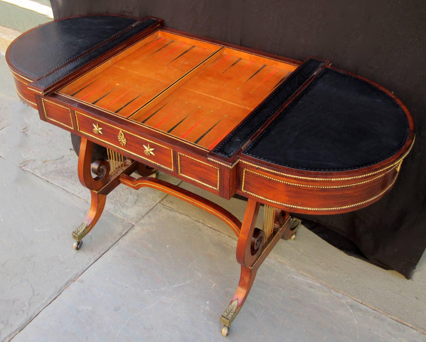 A fine Regency Rosewood sofa gaming table attributed to noted English furniture maker Gillows of Lancaster & London, circa 1815, featuring its original reversible chess and backgammon boards, brass beadwork and lyre base with fine bronze casters.