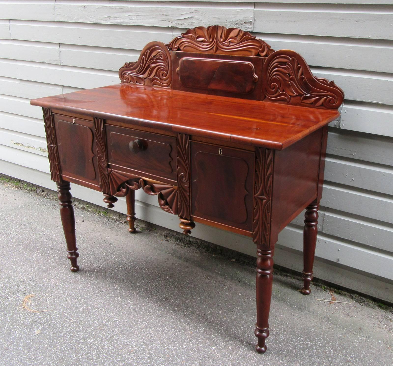 A fine West Indies Regency style cupping table from Barbados made of mahogany and cedrela, circa 1830, featuring exquisite carvings of local flora and fauna and three storage drawers. The drawers on either side of the table lock and the serving