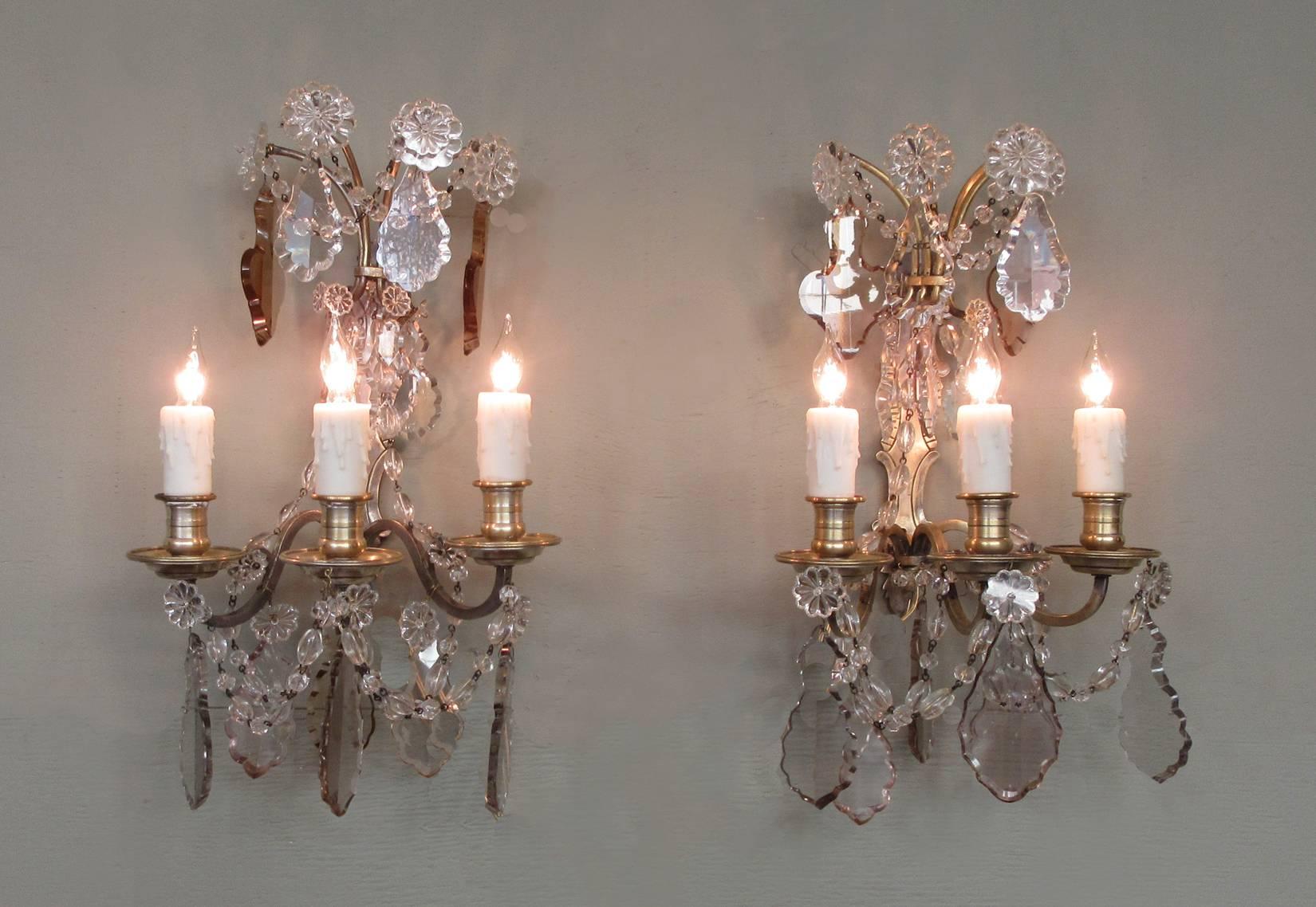 A pair of French Louis XIV crystal scones, circa 1910, featuring three candle arms, clear crystal rosettes and pendants with pale taupe and plum hues. The sconces have been rewired with new porcelain sockets.