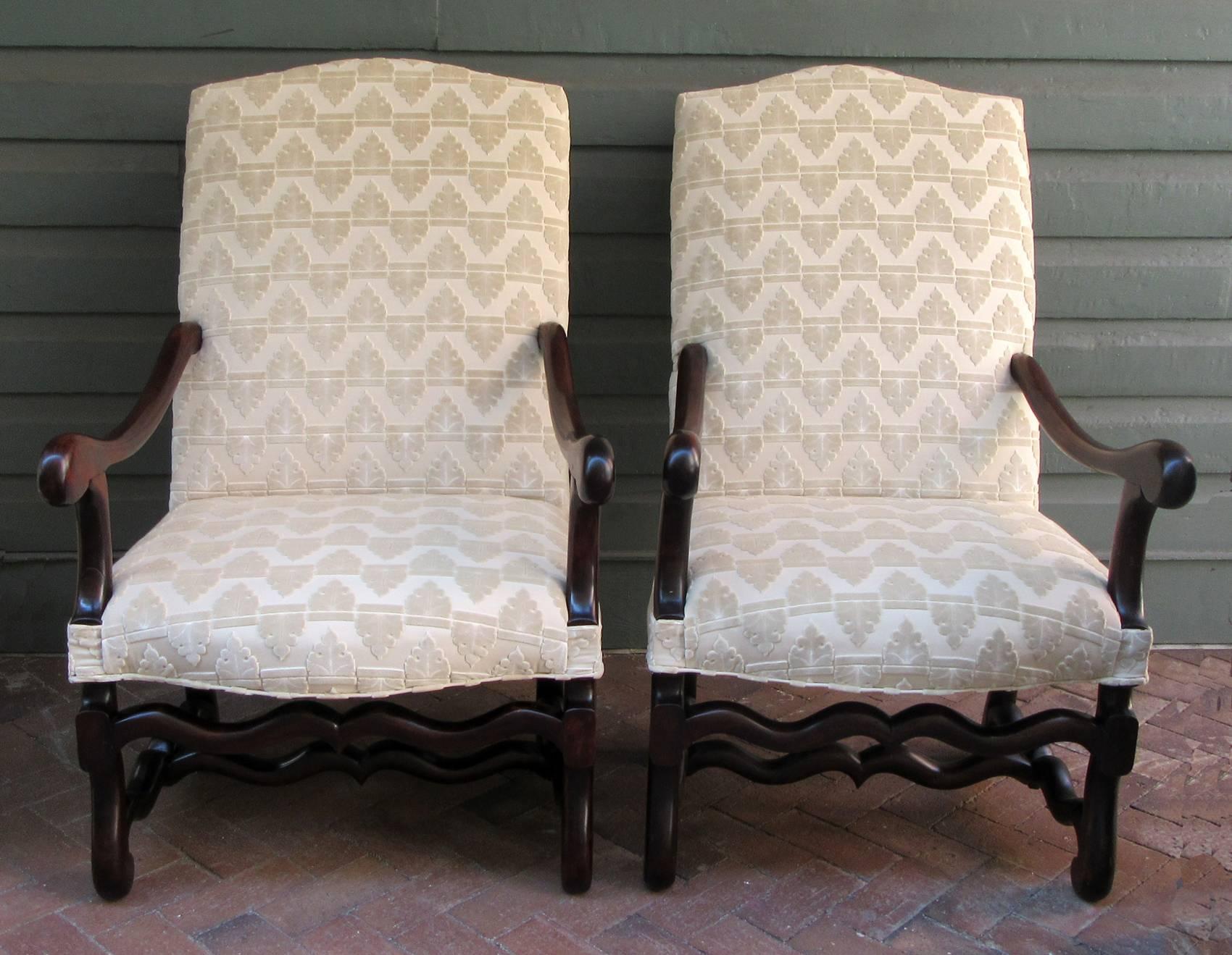 A handsome pair of French Louis XIII style Os de Mouton walnut armchairs, circa 1820, with ivory cut velvet upholstery and dark stain finish.