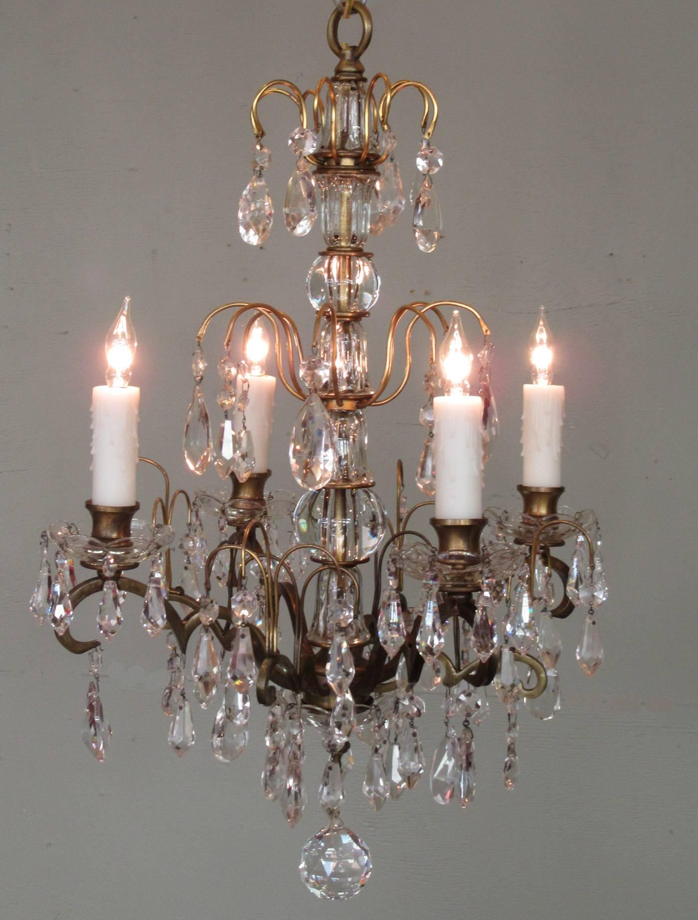 A smaller scale Italian chandelier, circa 1910, with bronze and glass stem adorned with crystal pendants, four candle bulbs with crystal and glass bobeches and finished with a cut crystal ball. The chandelier has been recently rewired with new